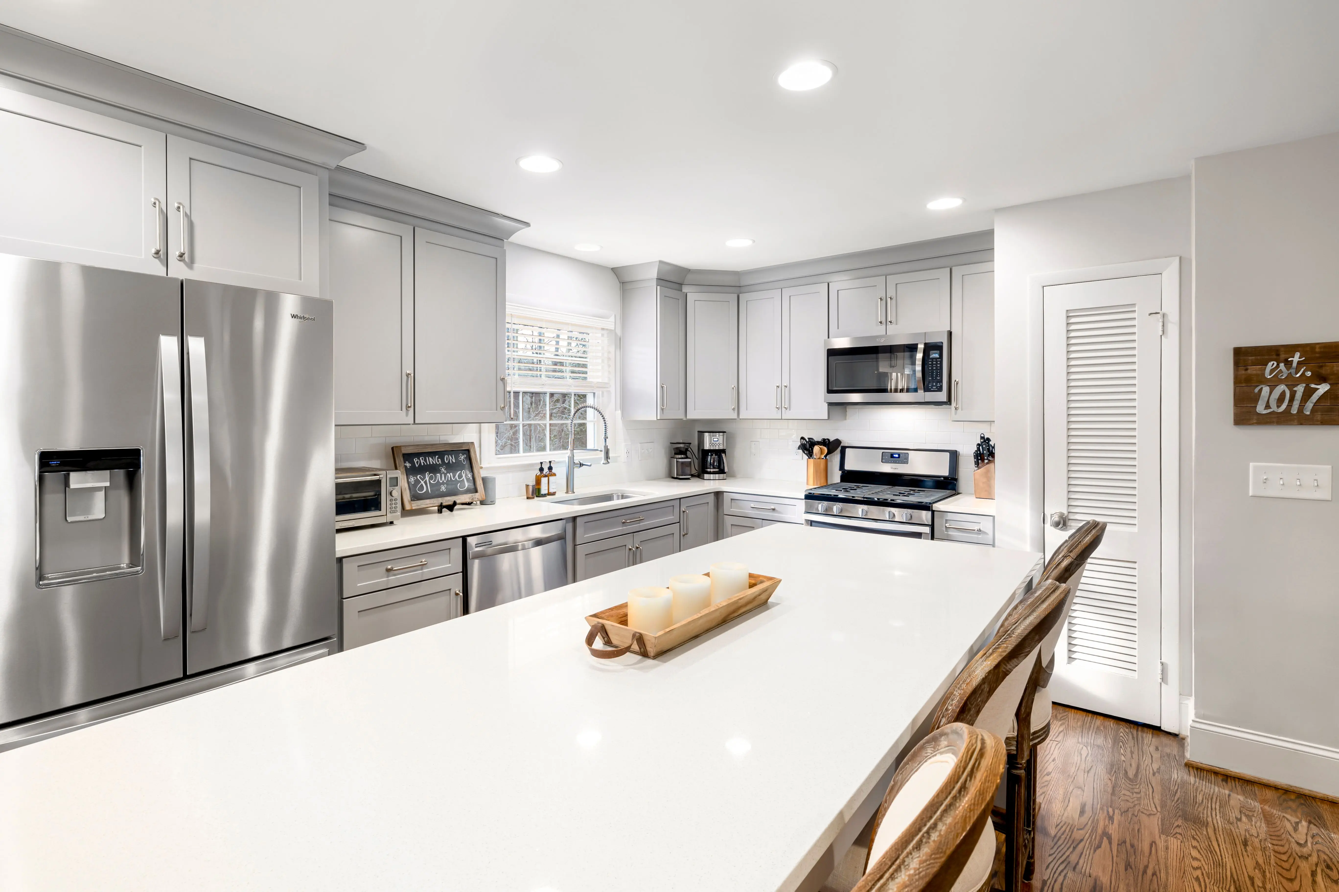 dark gray kitchen cabinets Bright and spacious minimalist kitchen featuring stainless steel appliances and a large central island.