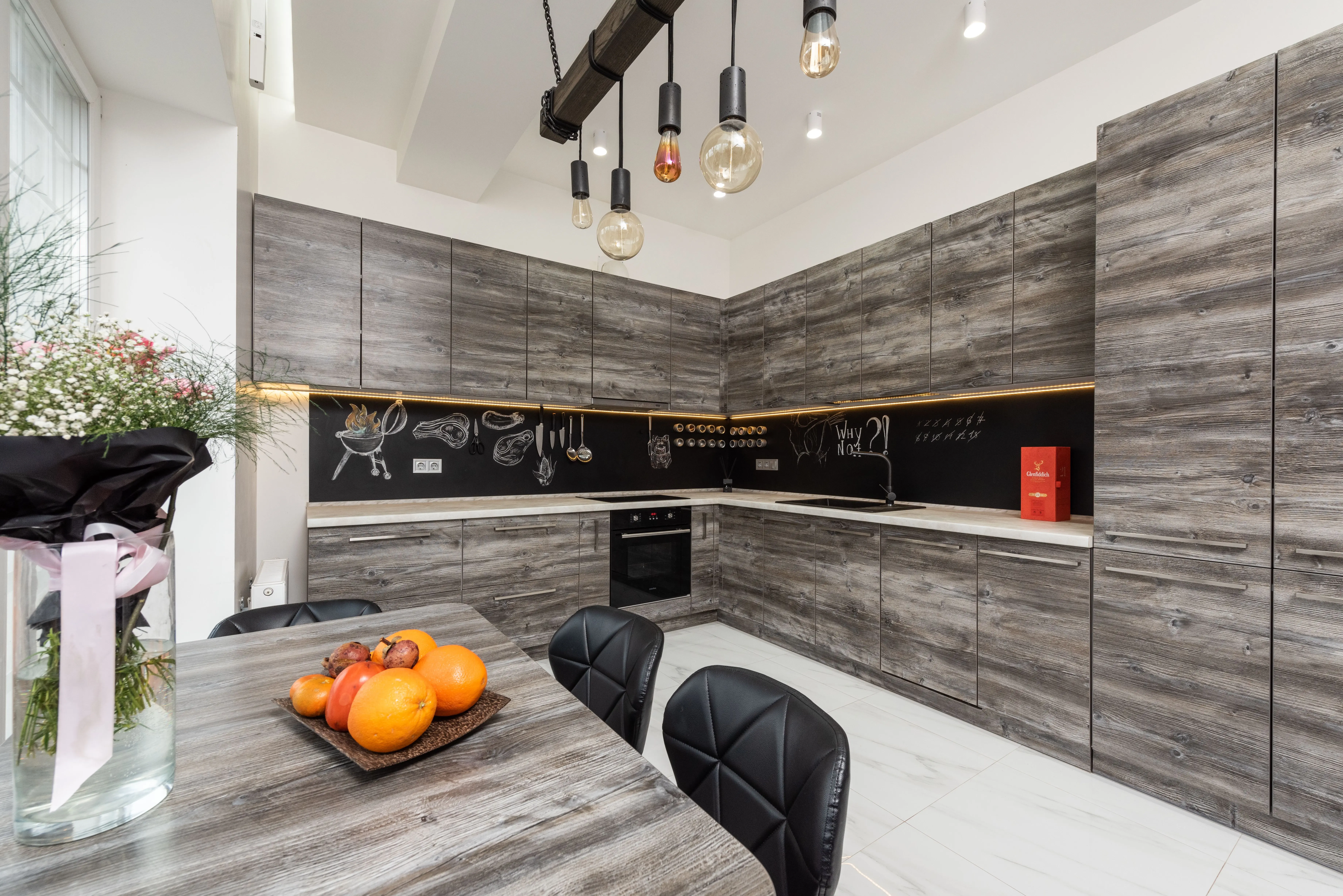farmhouse kitchen cabinets Table with bouquet and fruits placed near gray cupboards and modern kitchenware in spacious kitchen with lamps and creative design