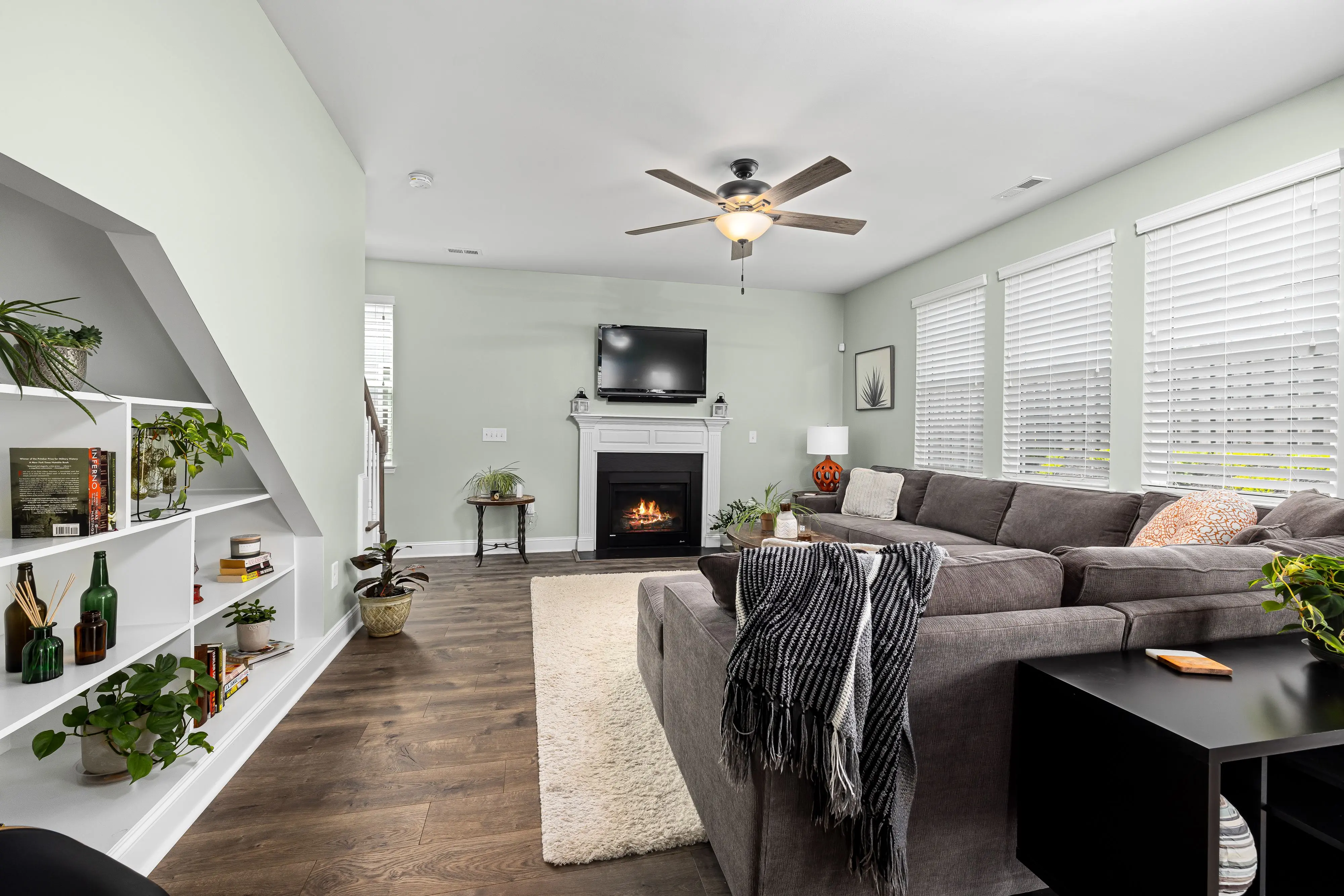 sectional green Stylish living room featuring a large sectional sofa, fireplace, and indoor plants for a cozy ambiance.