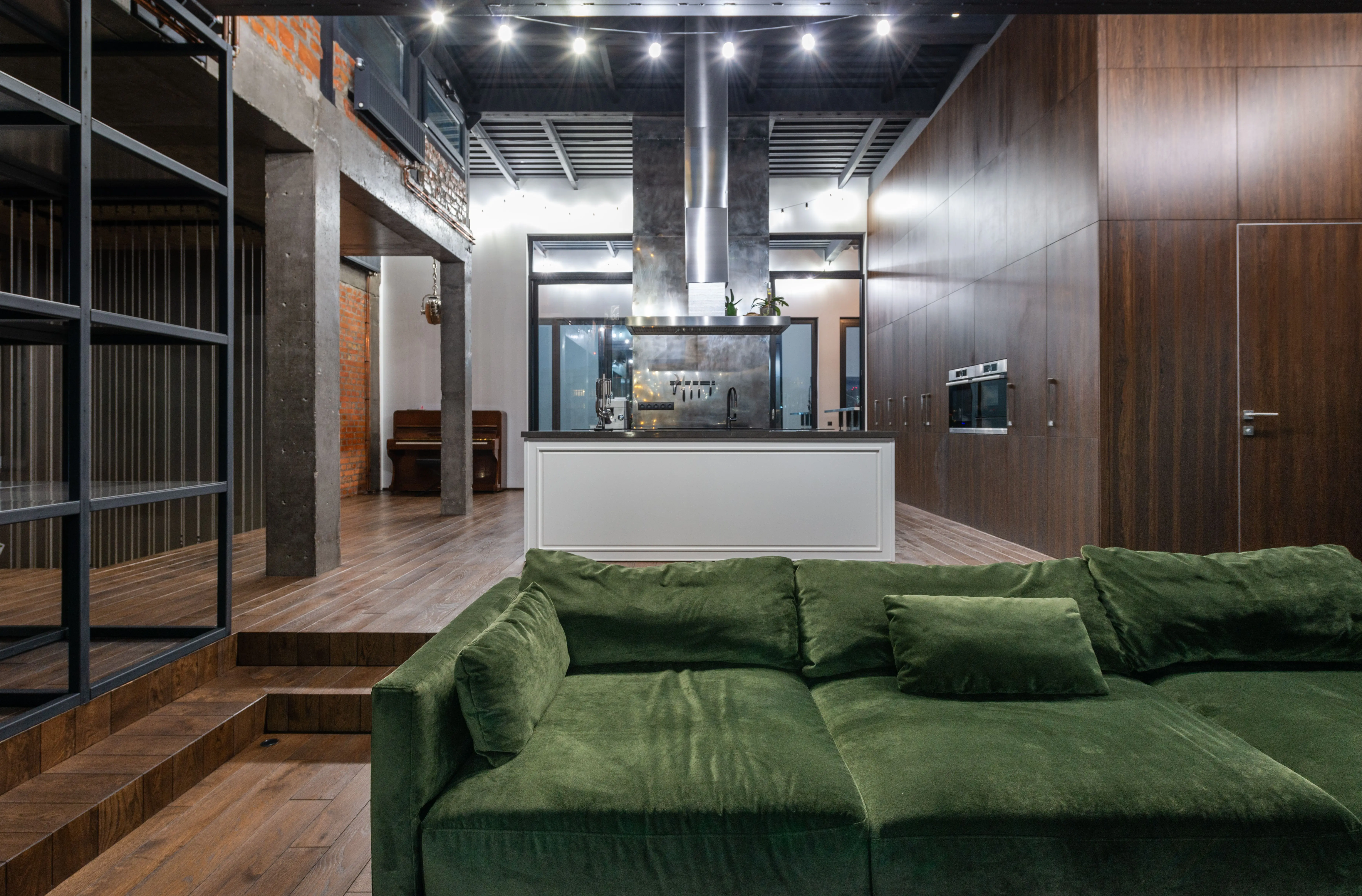 sectional green Comfortable green sofa placed in living room against kitchen zone in contemporary apartment