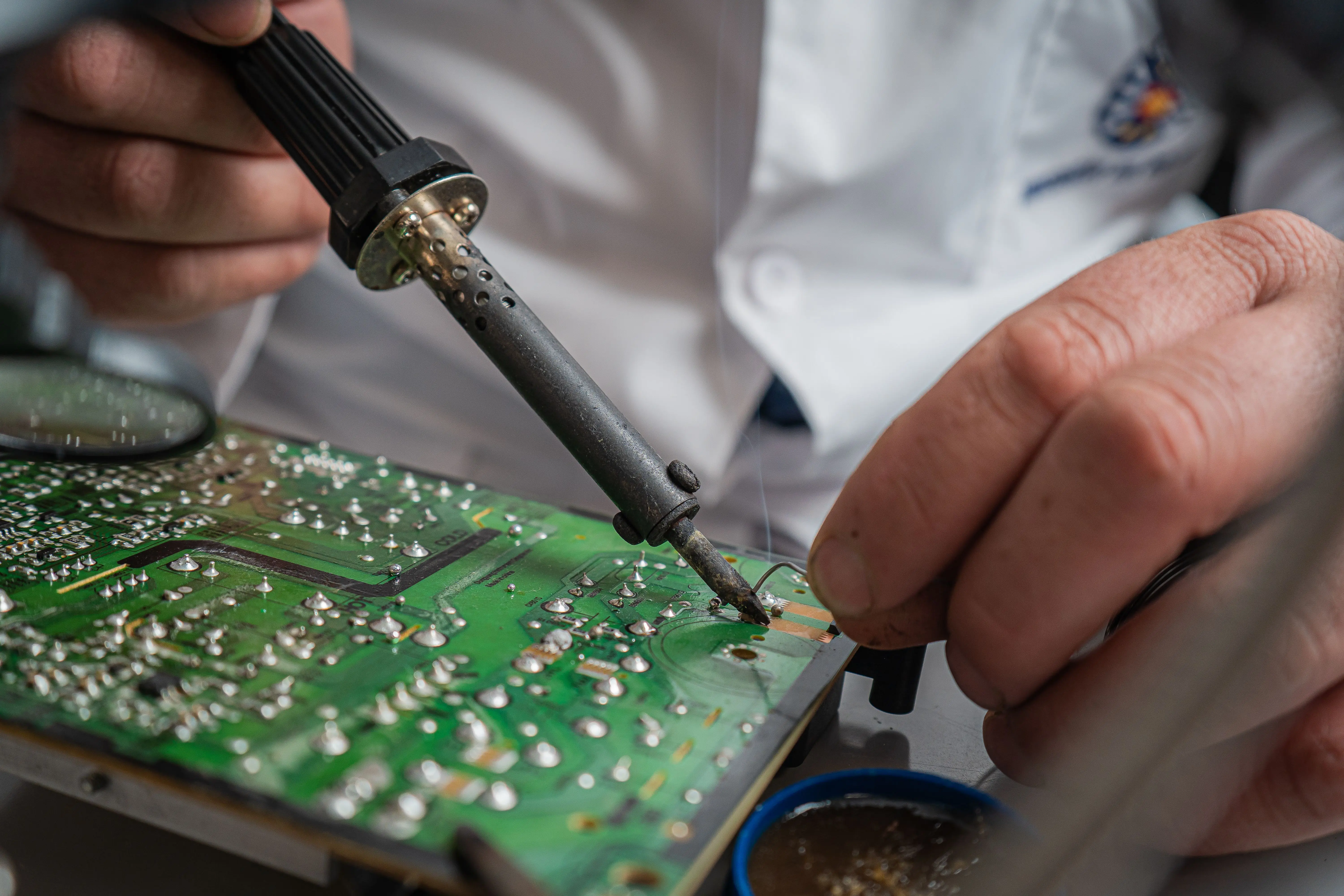 fence invisible cost Technician performing precise soldering on a circuit board for electronics repair.