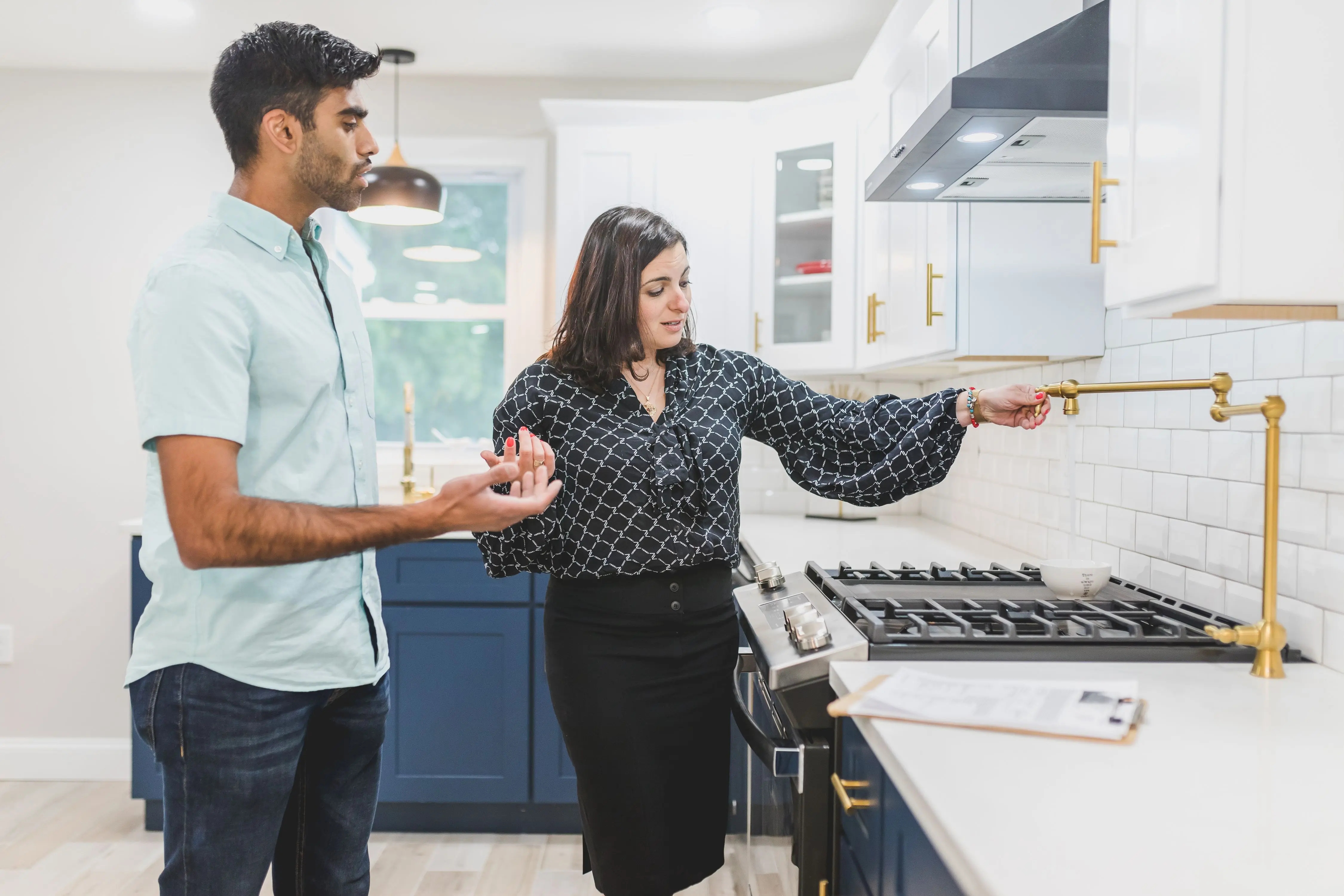 gold drawer pulls Real estate agent showing a modern kitchen interior with brass fixtures to a client.