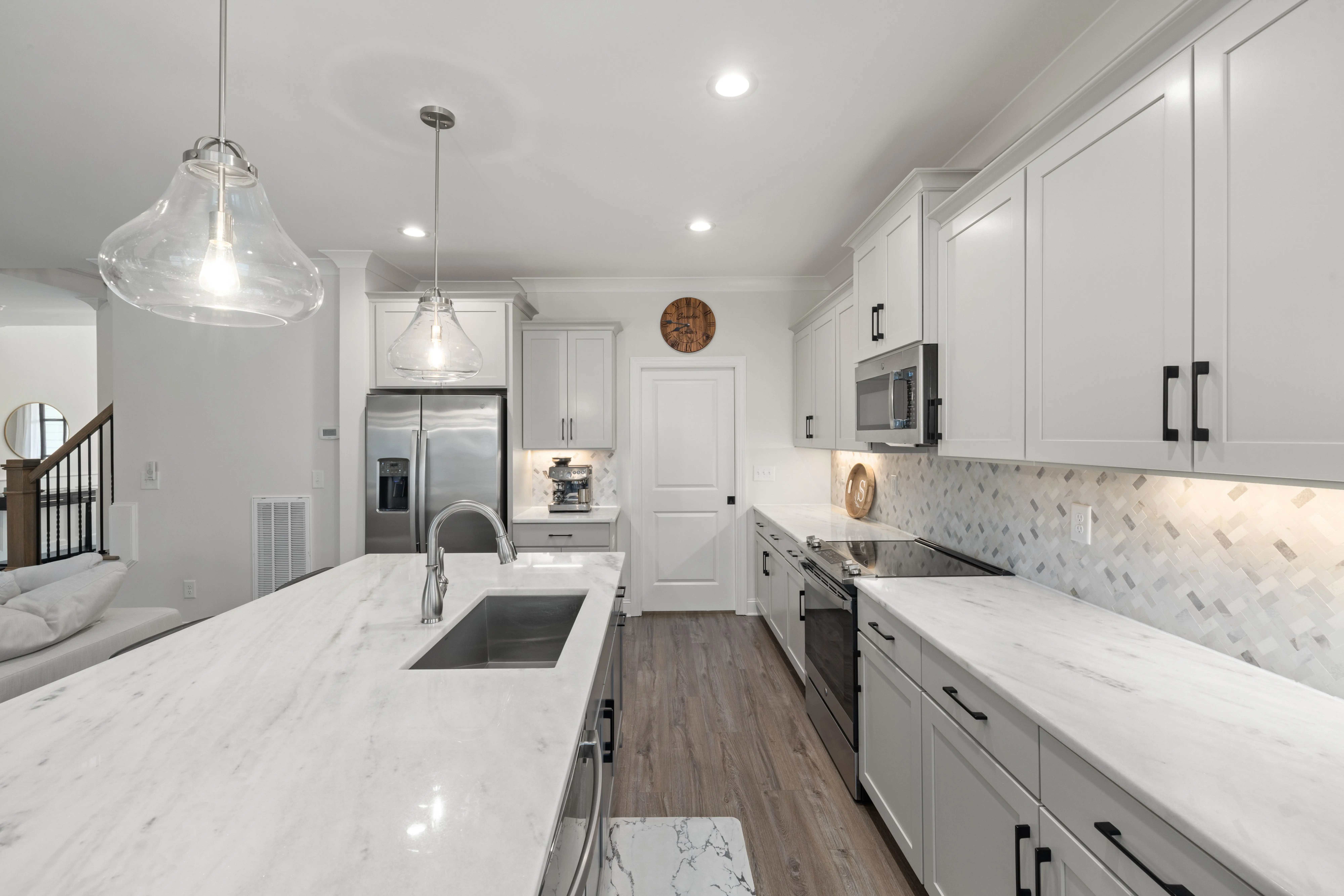 dark grey kitchen cabinets Elegant modern kitchen with marble countertops, stainless steel appliances, and pendant lighting.