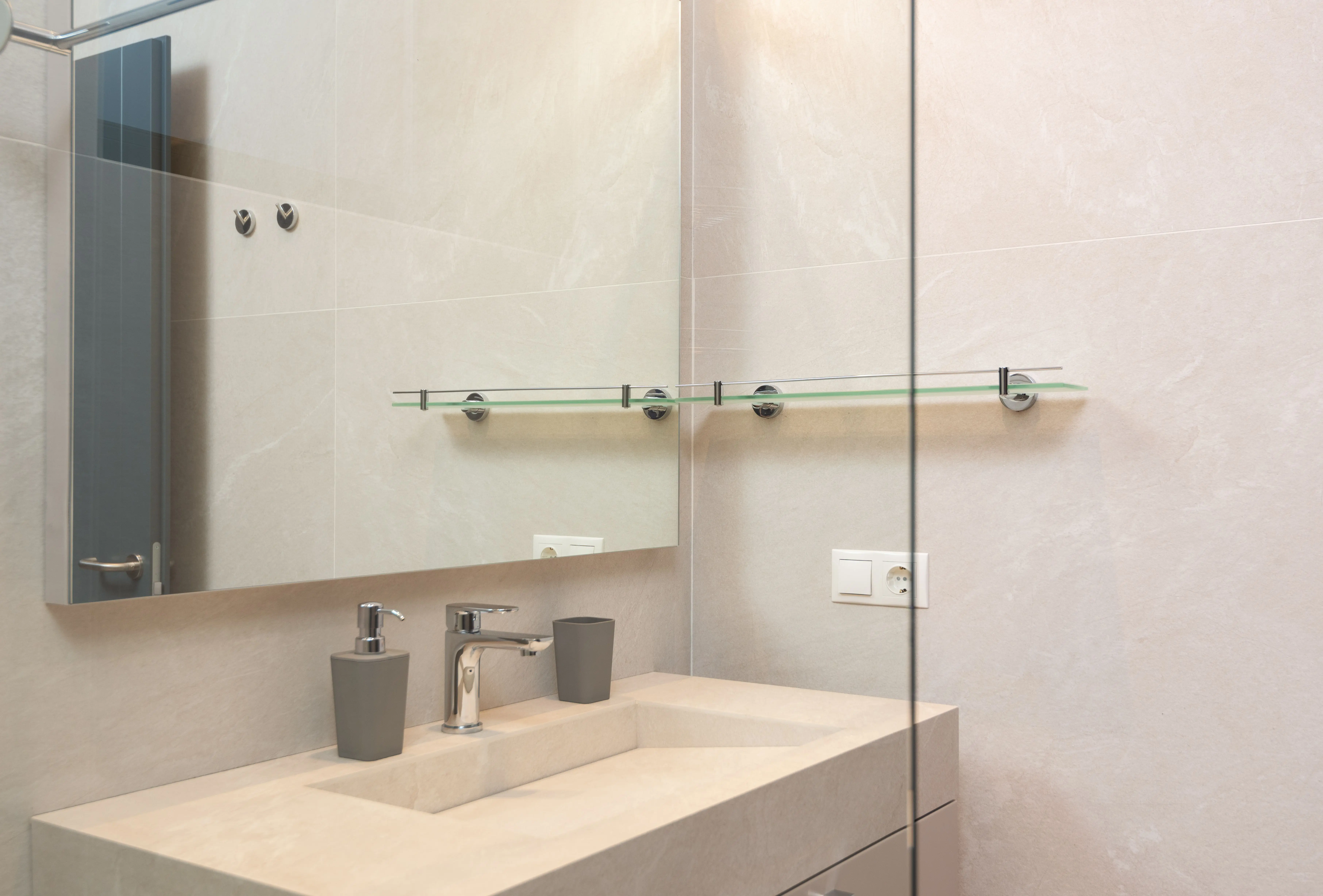 vanity shelves Through glass of shower cabin on sink and mirror in modern bathroom with tiled walls