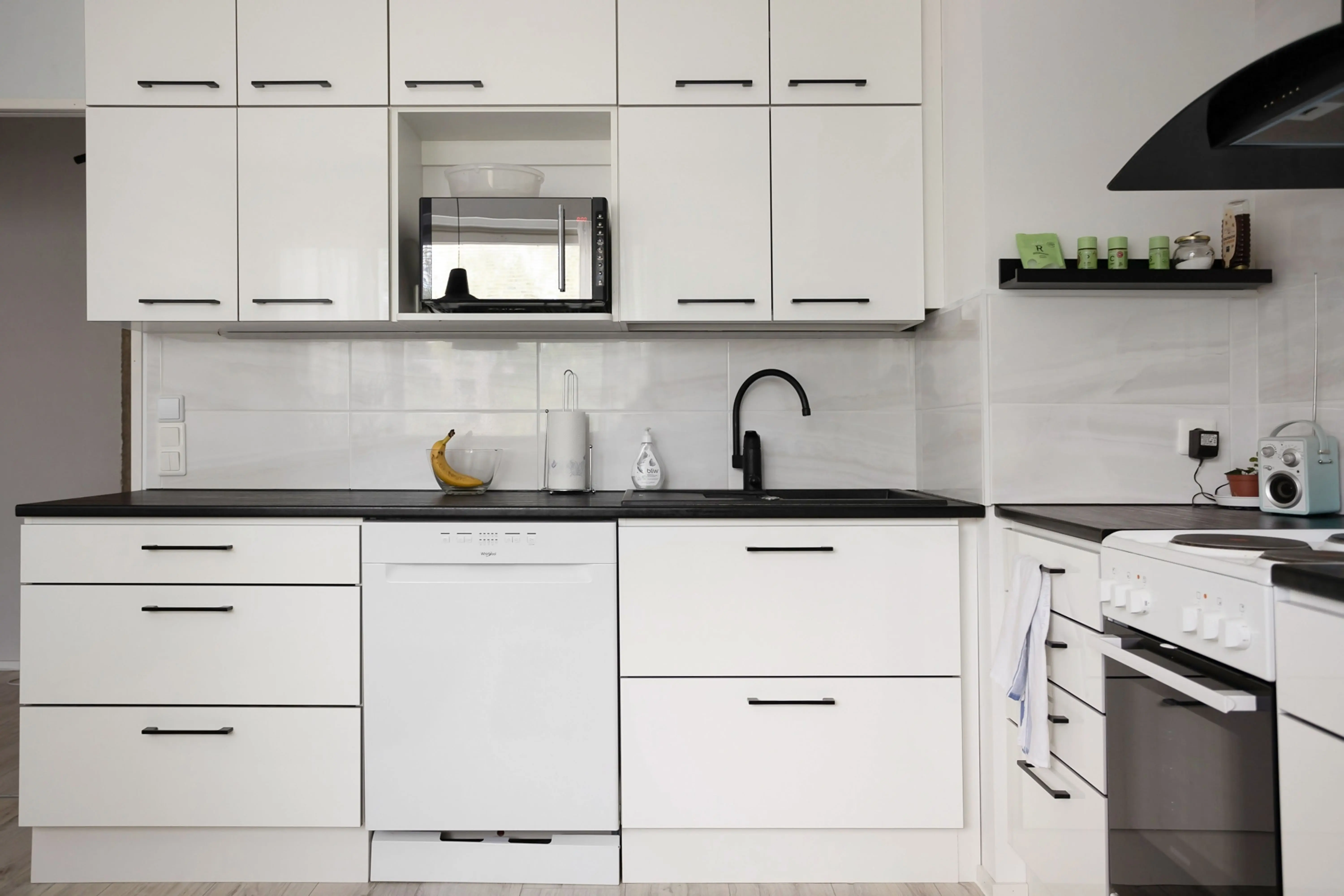 black cabinet hardware Sleek and modern white kitchen with appliances, showcasing contemporary interior design.
