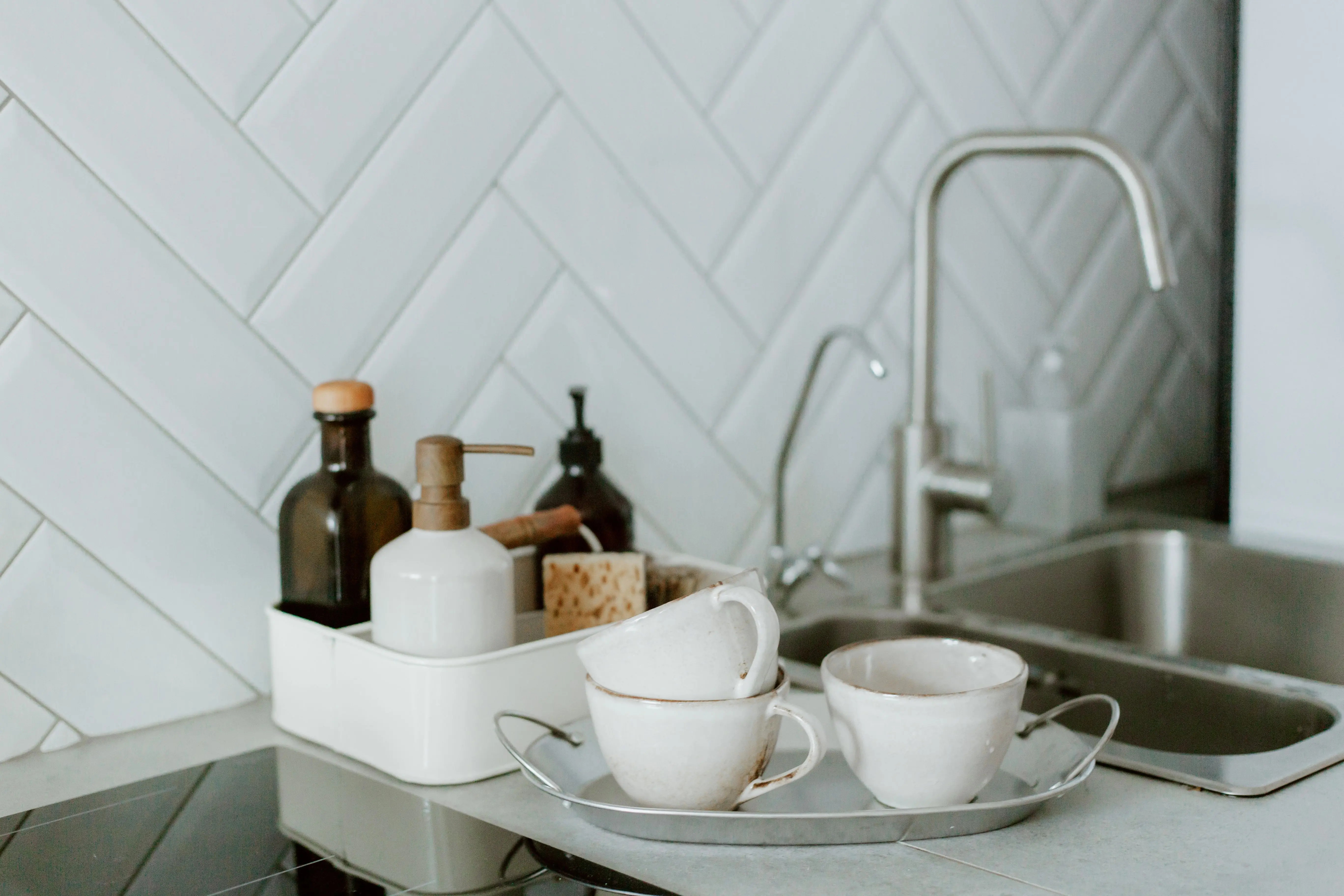 under sink cabinet A simple and clean kitchen counter setup featuring tea cups and soap dispensers.