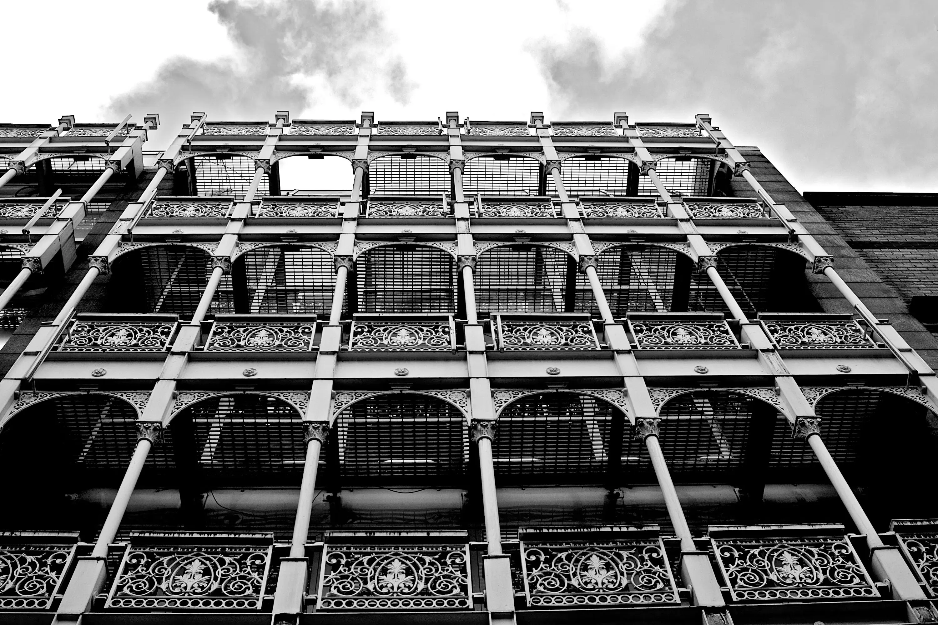 wrought iron patio furniture sets Black and white photo showcasing ornate ironwork on a historical building facade.