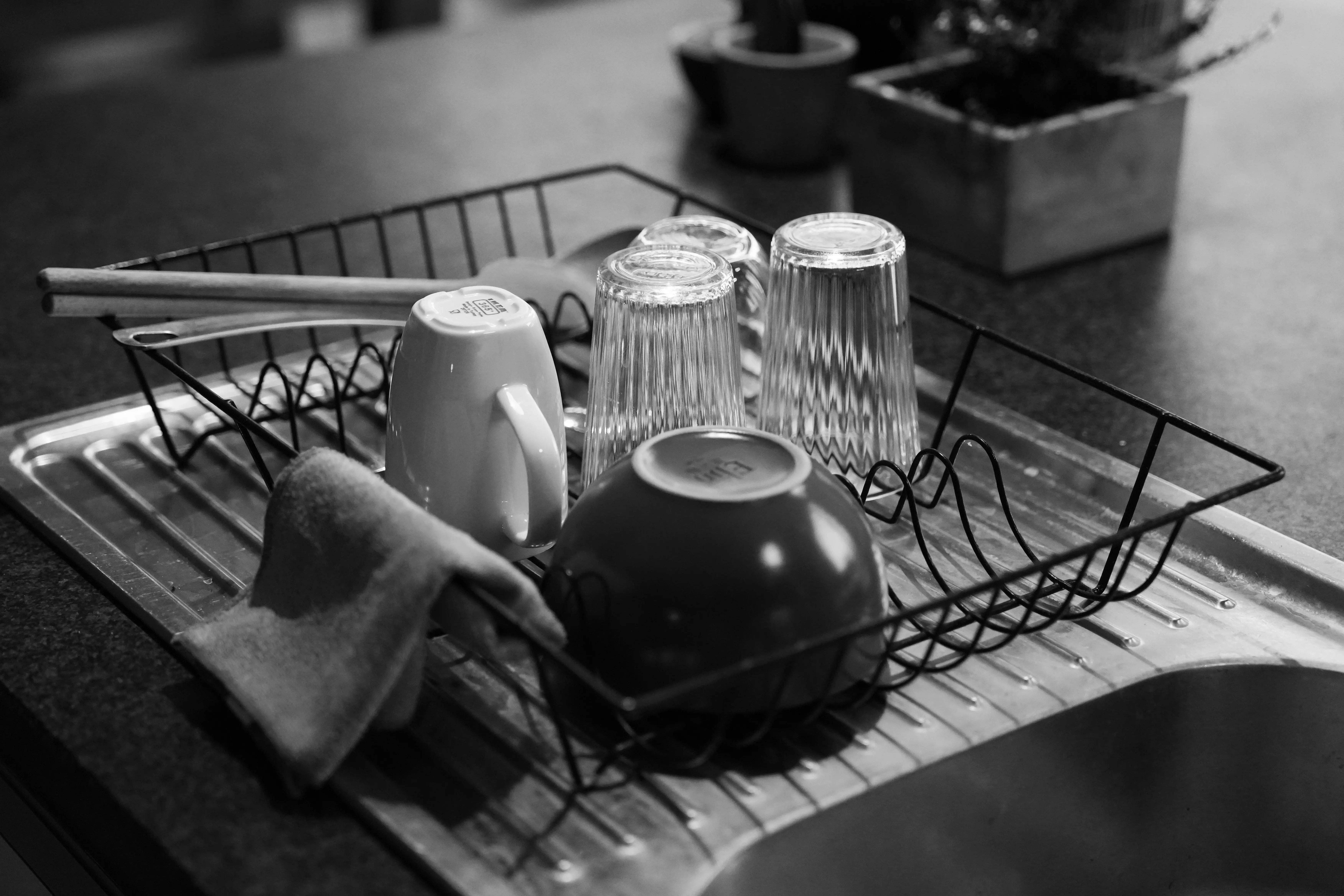 plate racks Black and white shot of a dish rack with glass and ceramic kitchenware.