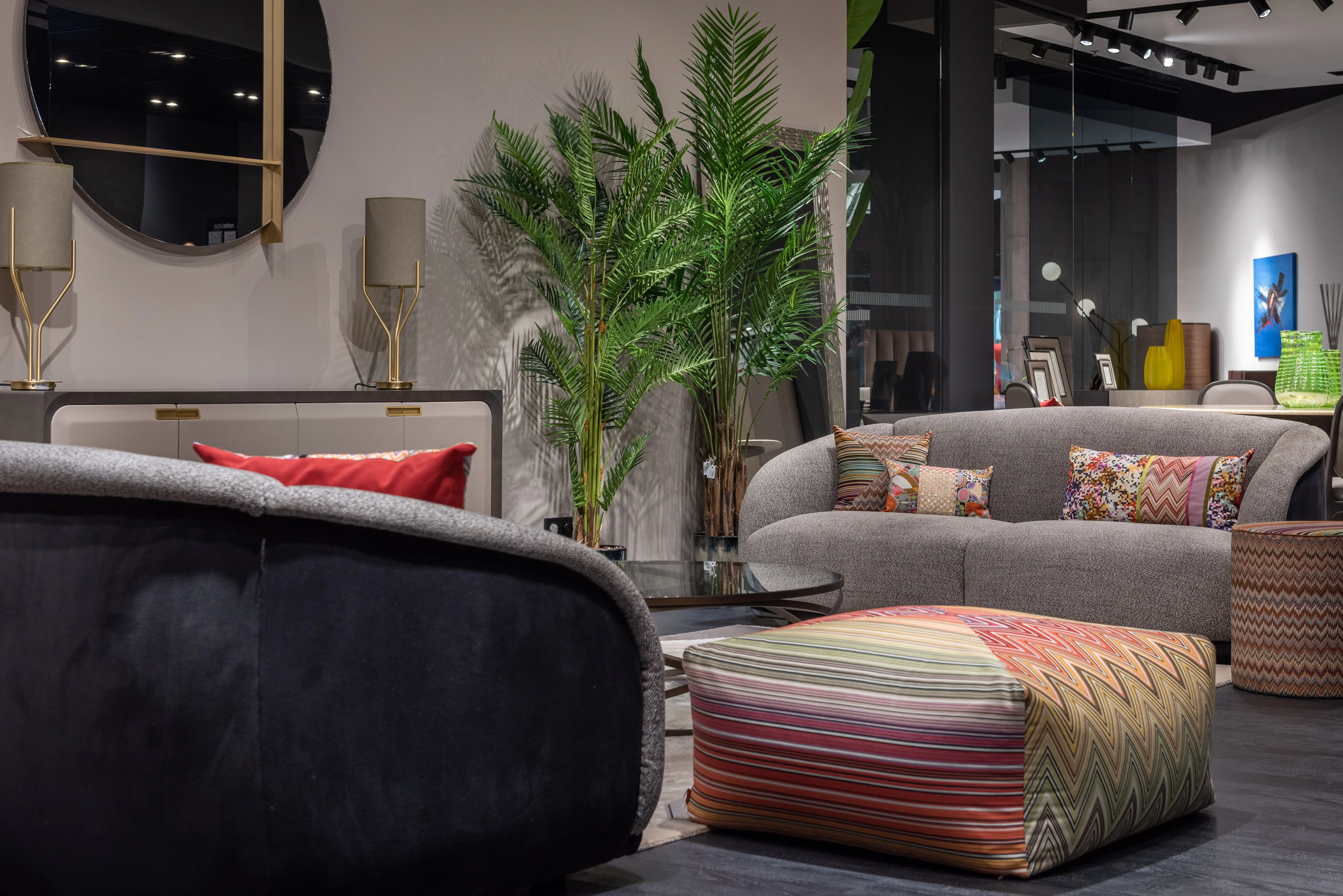 pouf coffee table Comfortable sofas with cushions and pouf placed in creative eclectic styled living room decorated with potted green palm trees in modern apartment