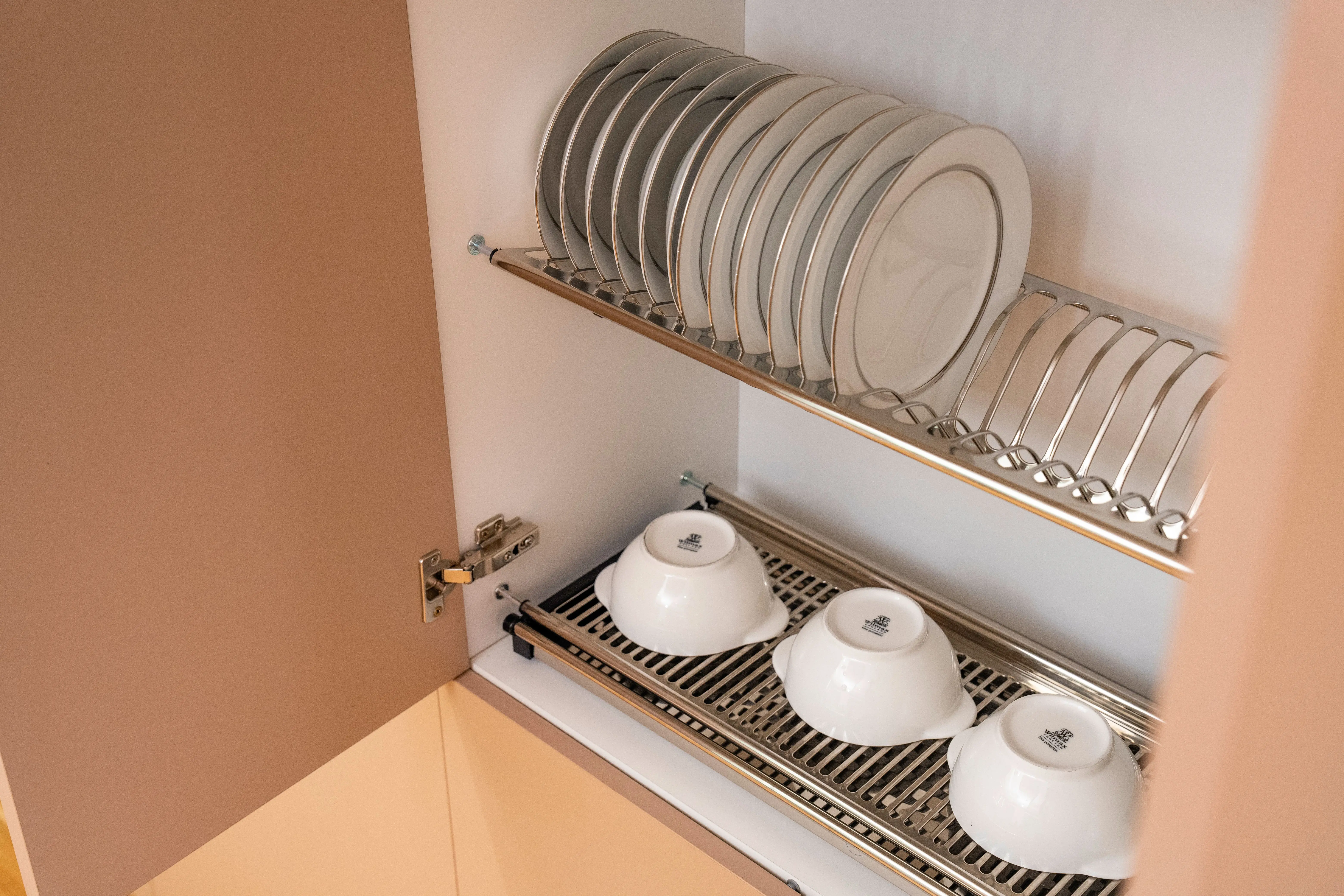 plate racks A clean and organized kitchen cabinet displaying plates and bowls on a drying rack.