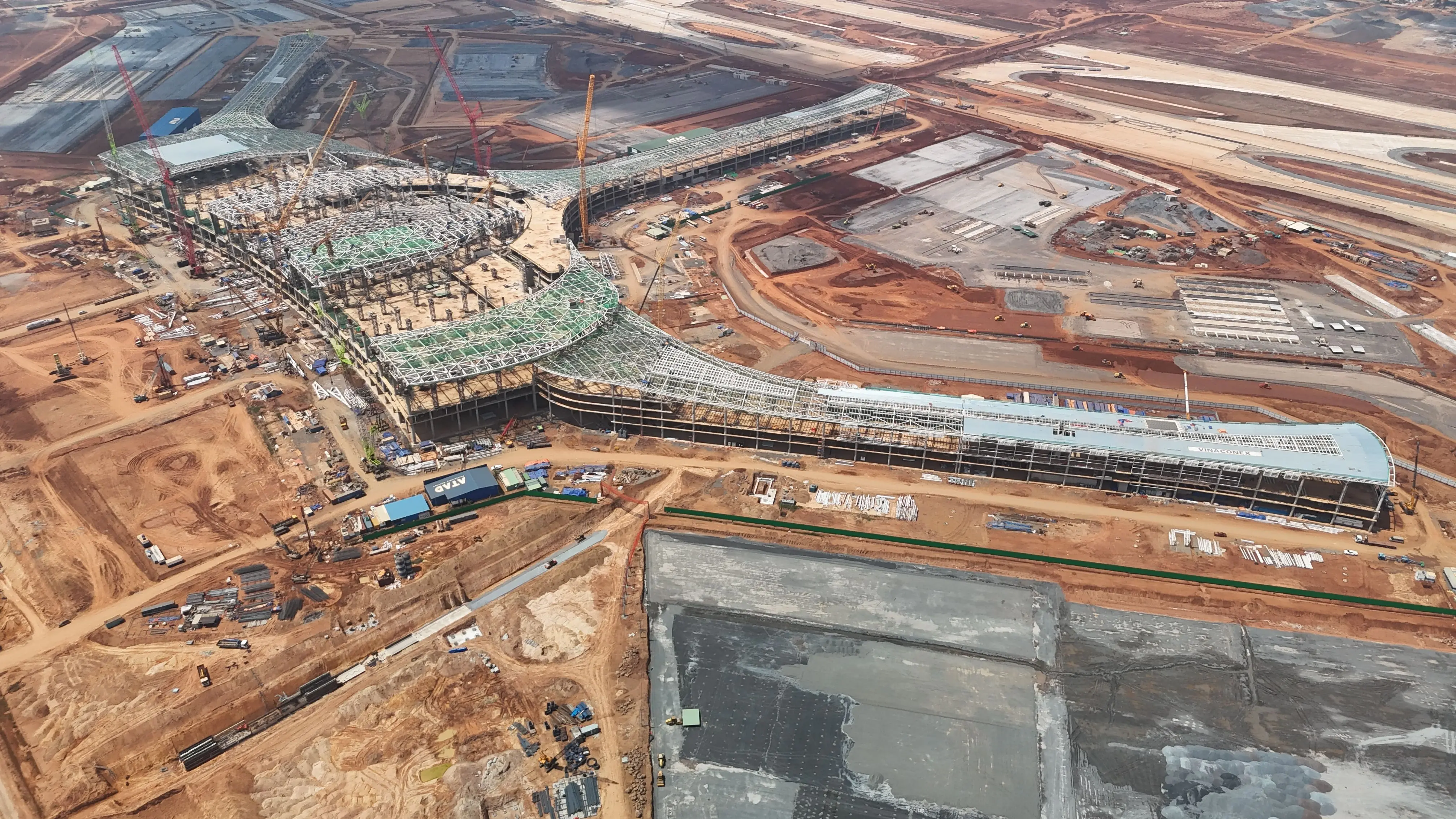 wall primer Expansive aerial shot of a construction site with cranes and building foundations in Đồng Nai, Việt Nam.