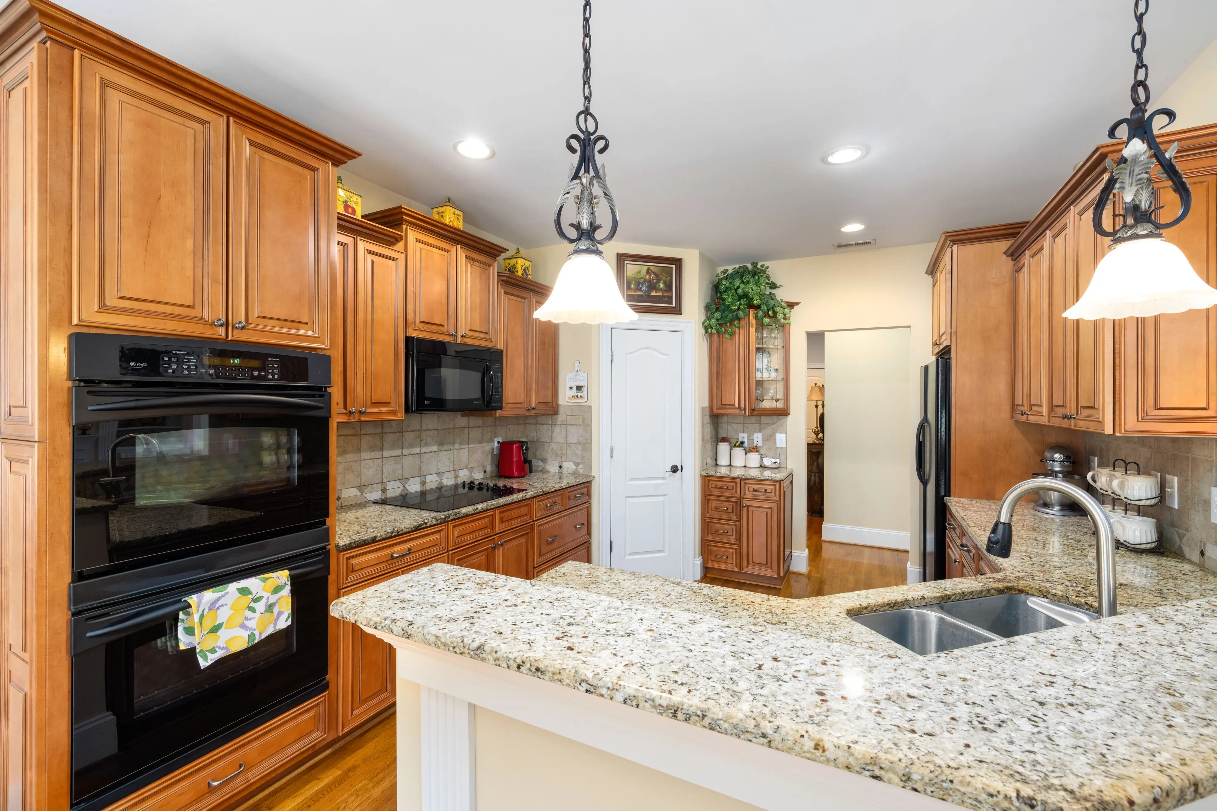 red granite Spacious kitchen featuring wooden cabinets, granite countertops, and modern appliances.