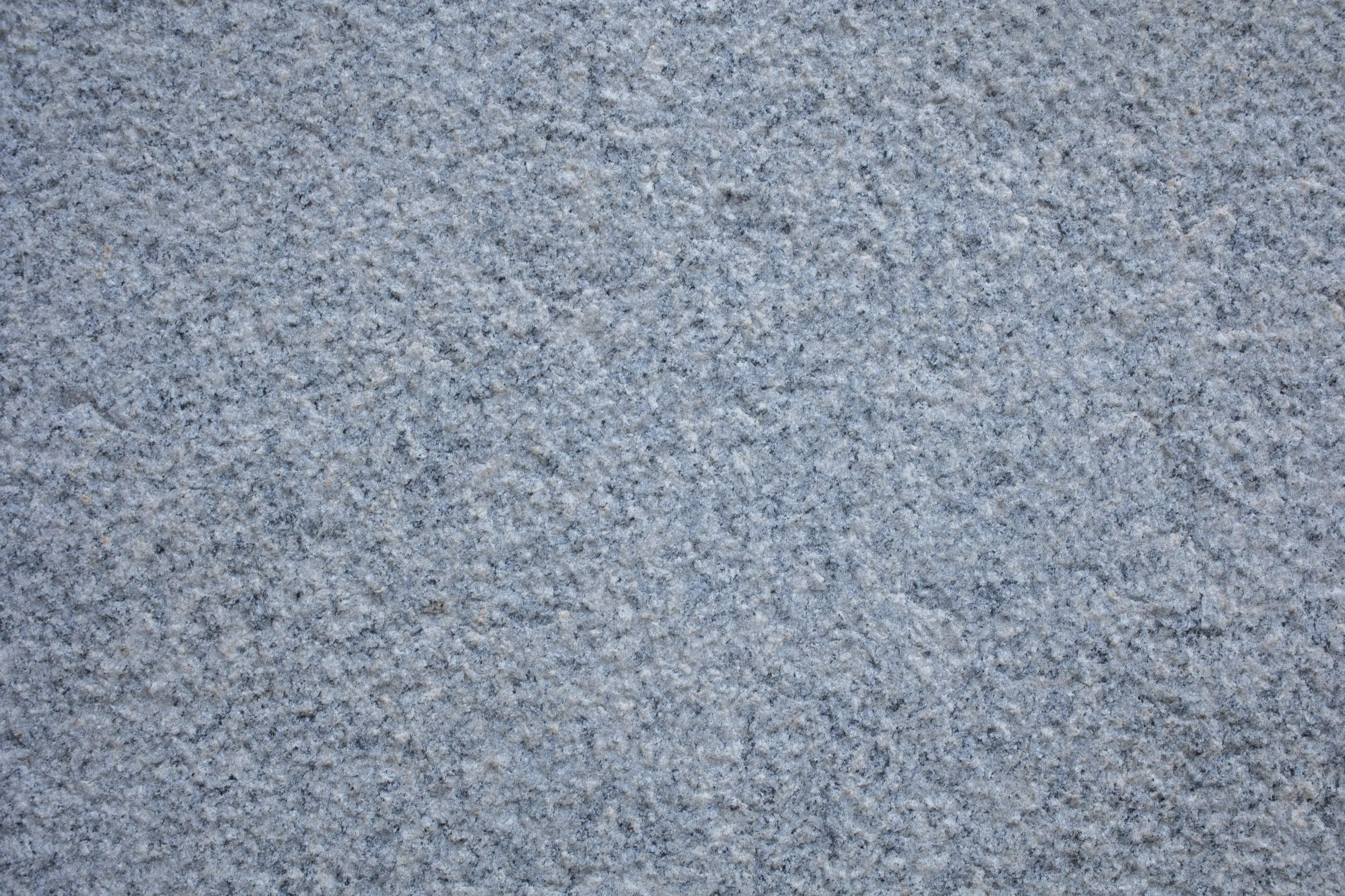 red granite Detailed close-up texture of a rough concrete pavement, showcasing its unique surface pattern.