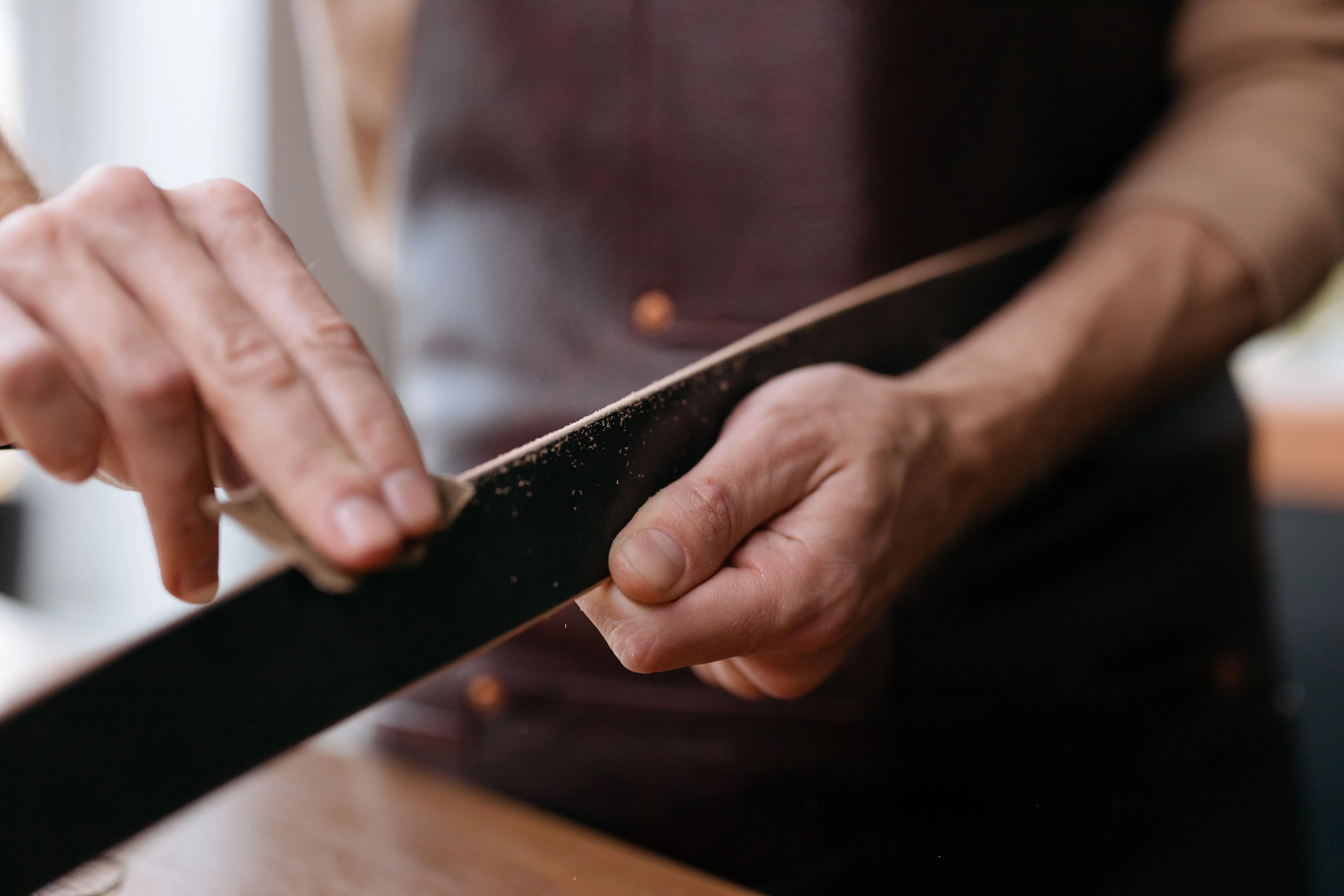 white stain Close-up of hands sanding a wooden strip with sandpaper in a workshop setting.