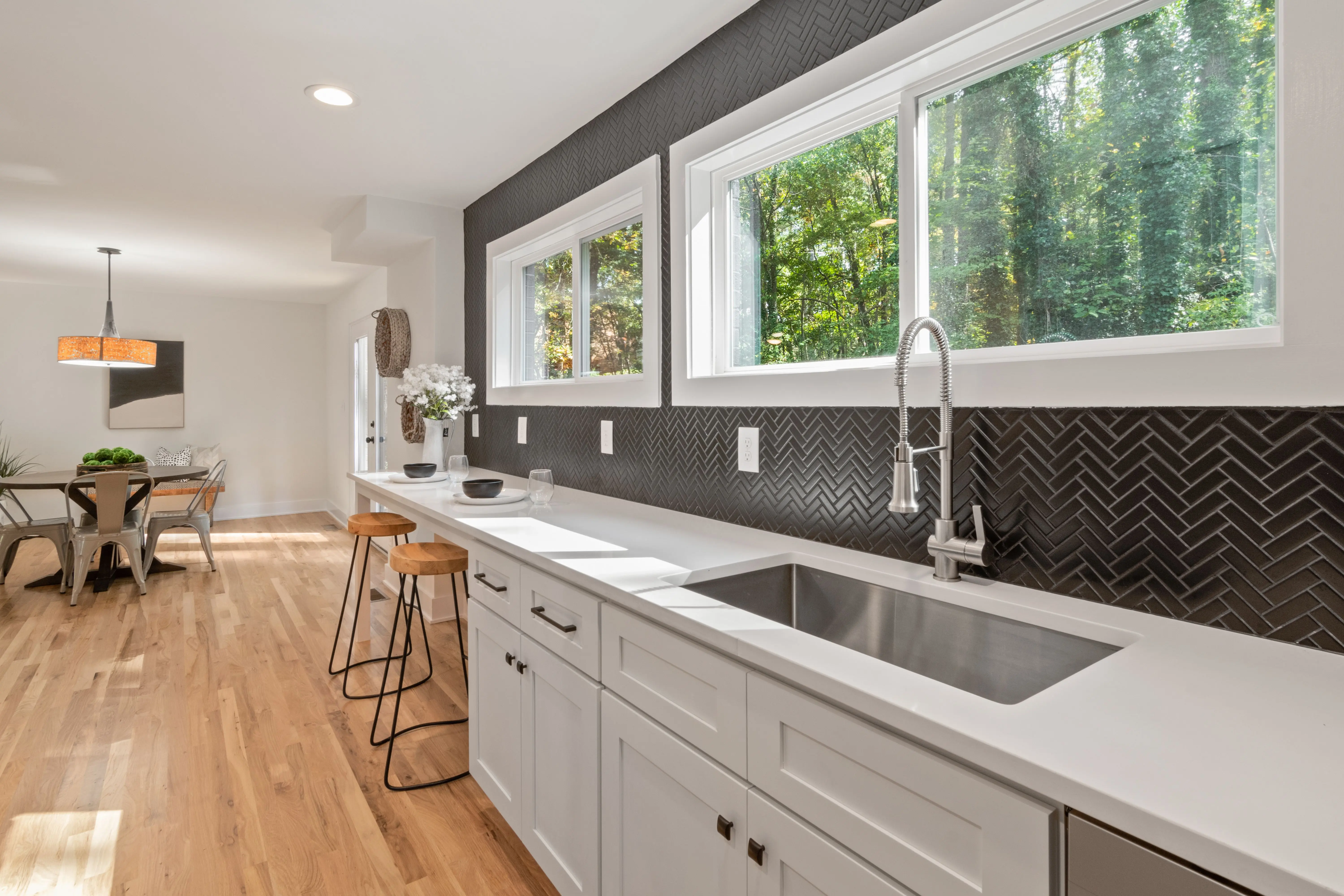 black backsplash Stylish modern kitchen with sleek fixtures, windows, and wooden floor.
