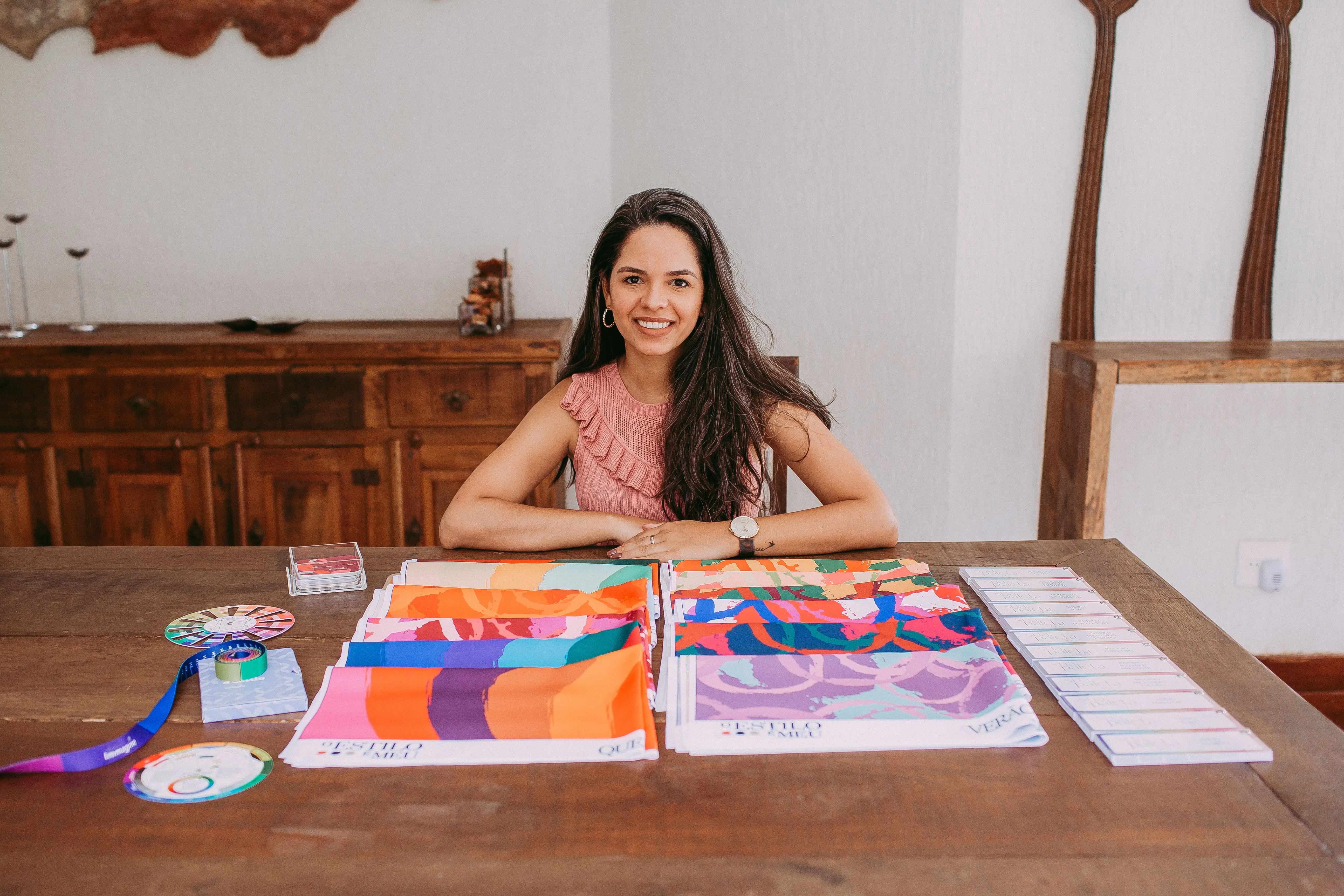studio room ideas Smiling woman designer showcasing vibrant fabric samples at wooden table.