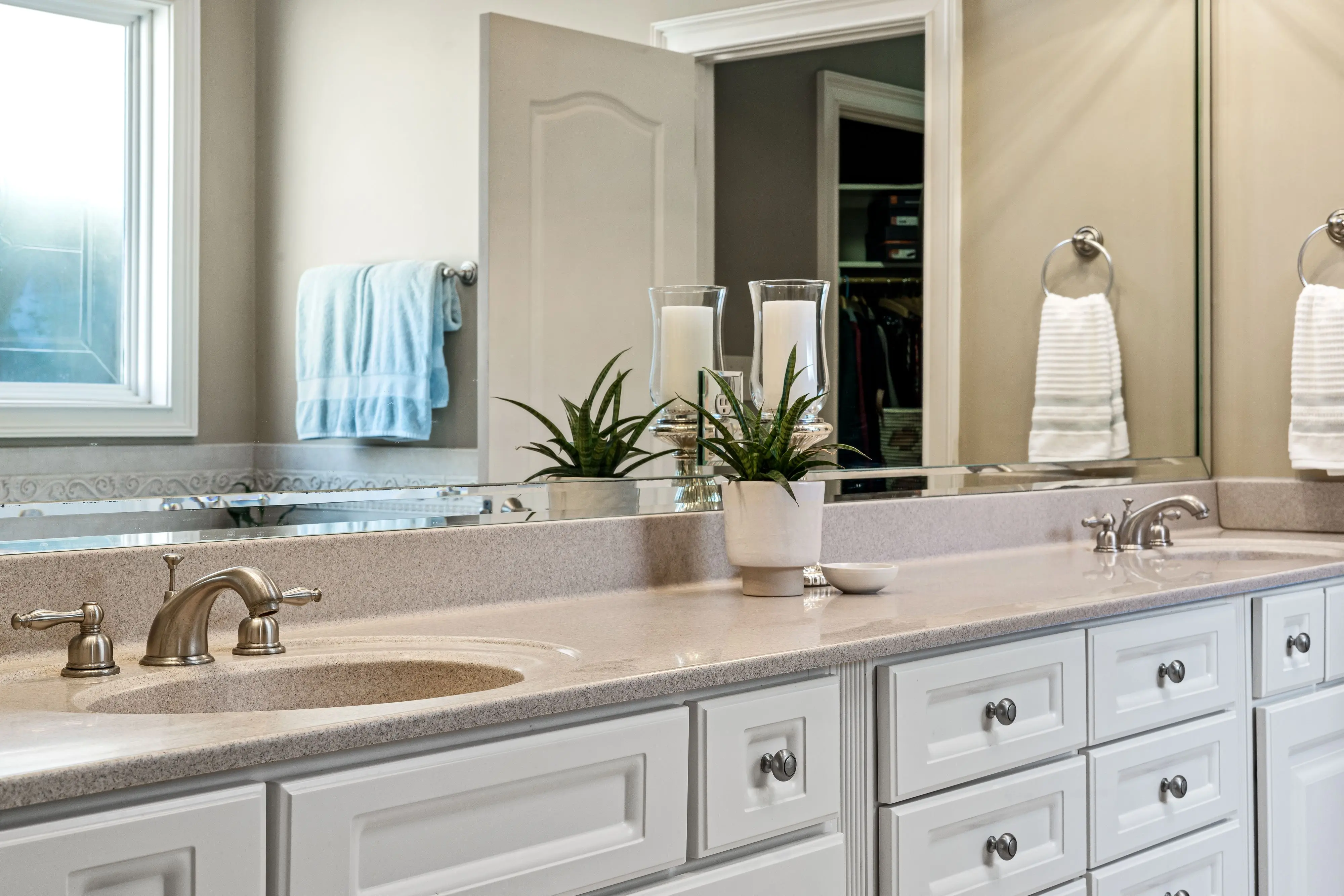 wood bathroom vanities Modern bathroom featuring minimalist design with white cabinets, large mirror, and stylish faucets.