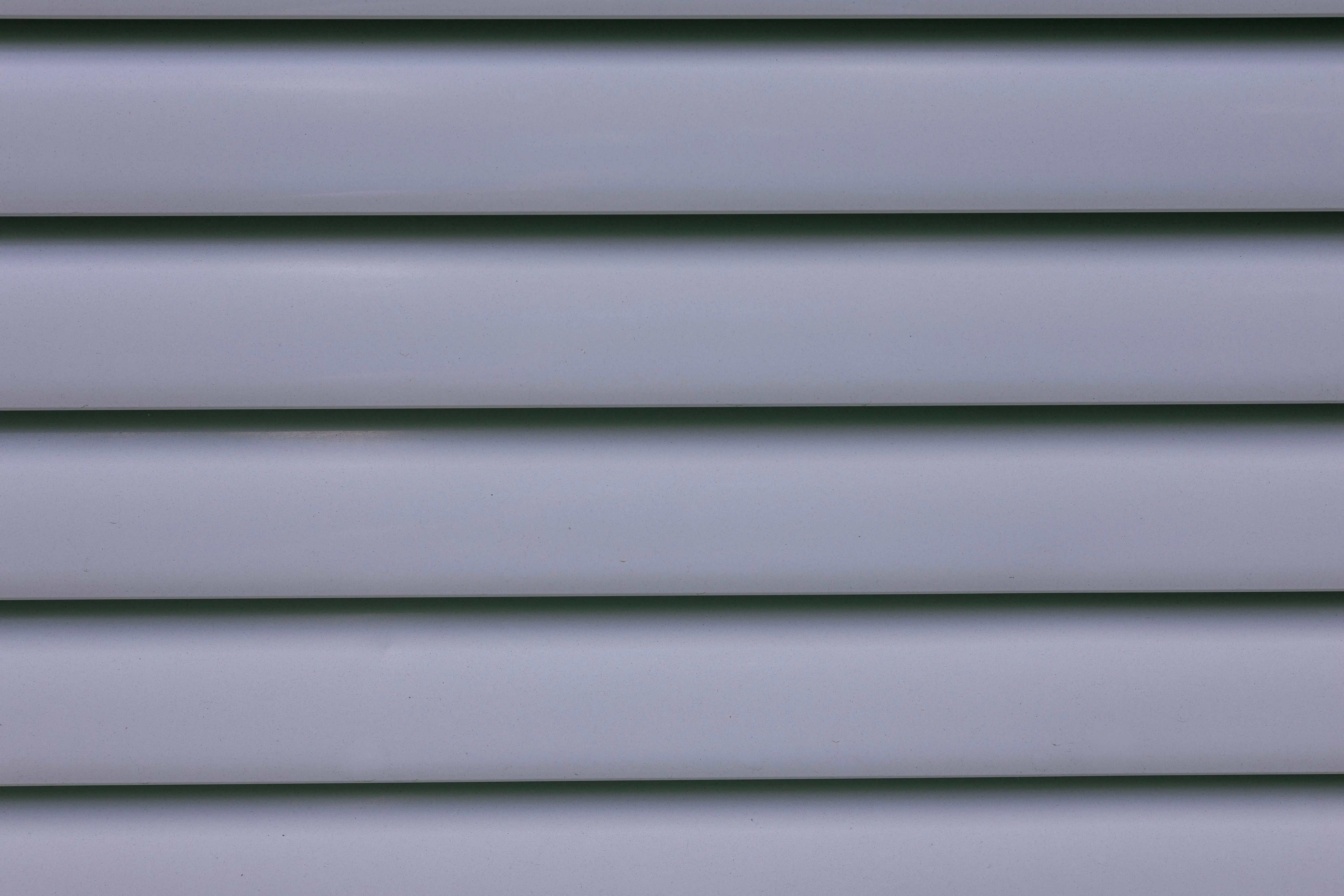 vinyl fence parts Detailed close-up of gray layered wall paneling showing lines and shadows.