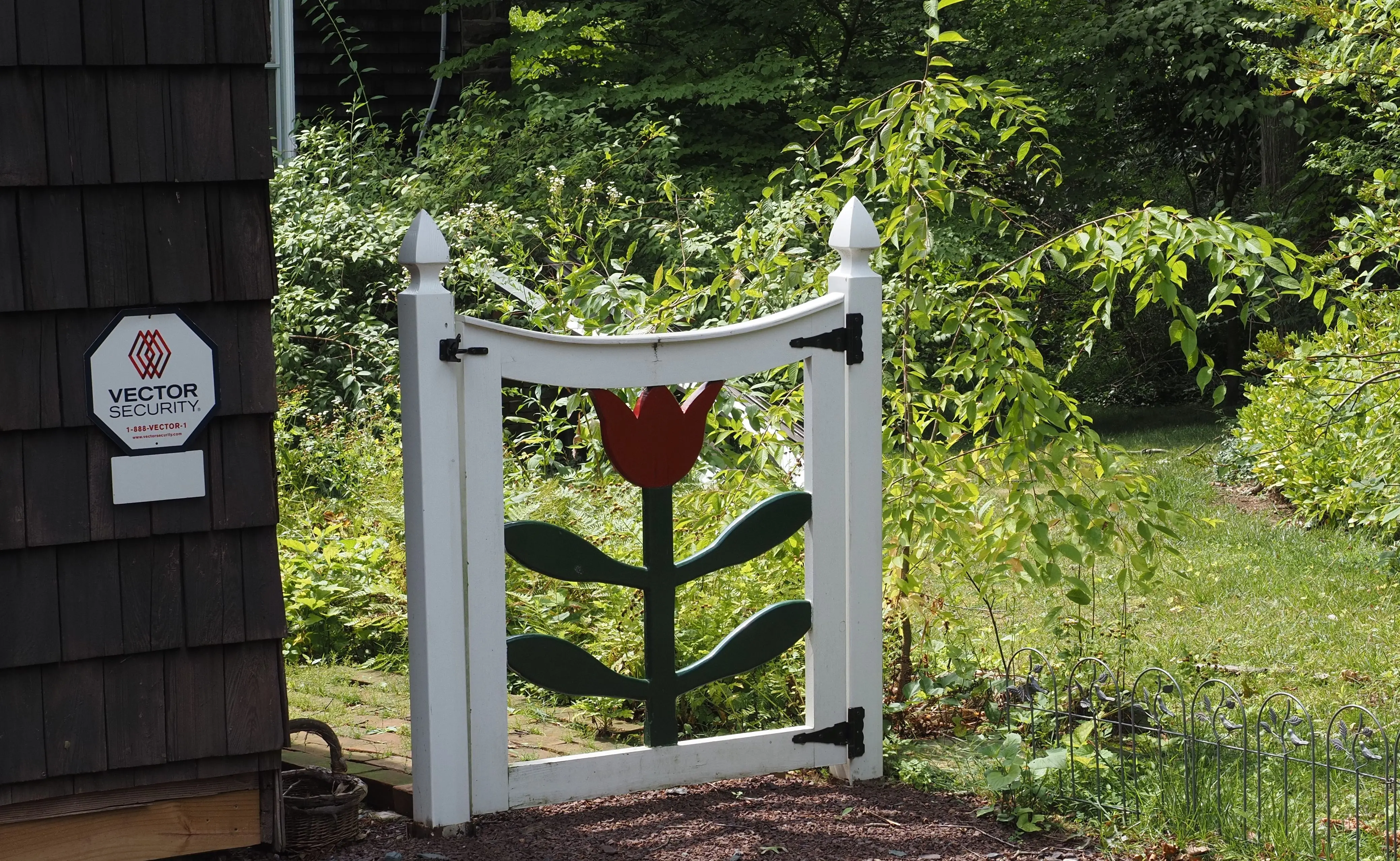vinyl fence parts Whimsical garden gate with tulip design in lush greenery, Doylestown, PA.