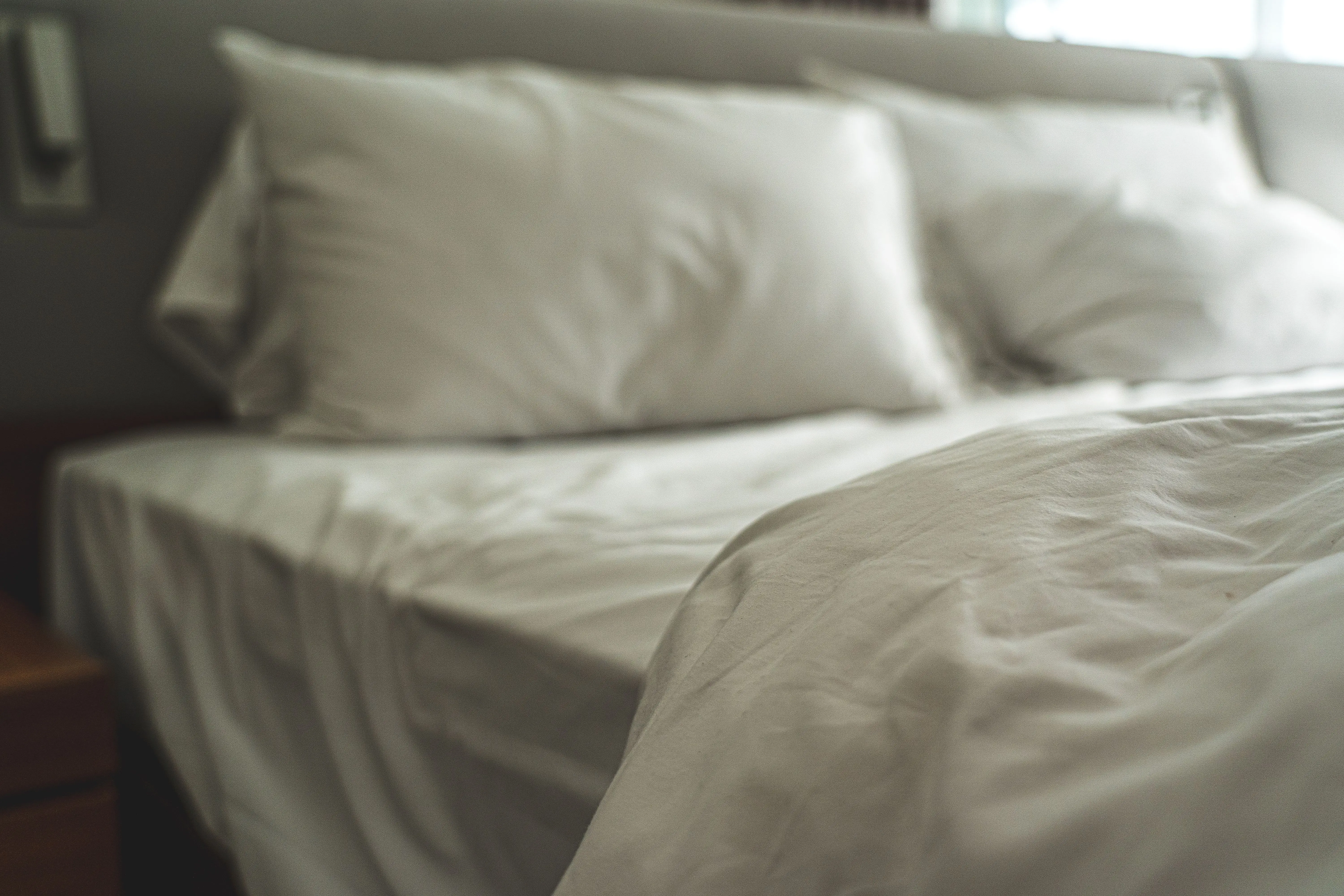 white pillow Elegant white bed linen with soft pillows creating a warm and inviting atmosphere.