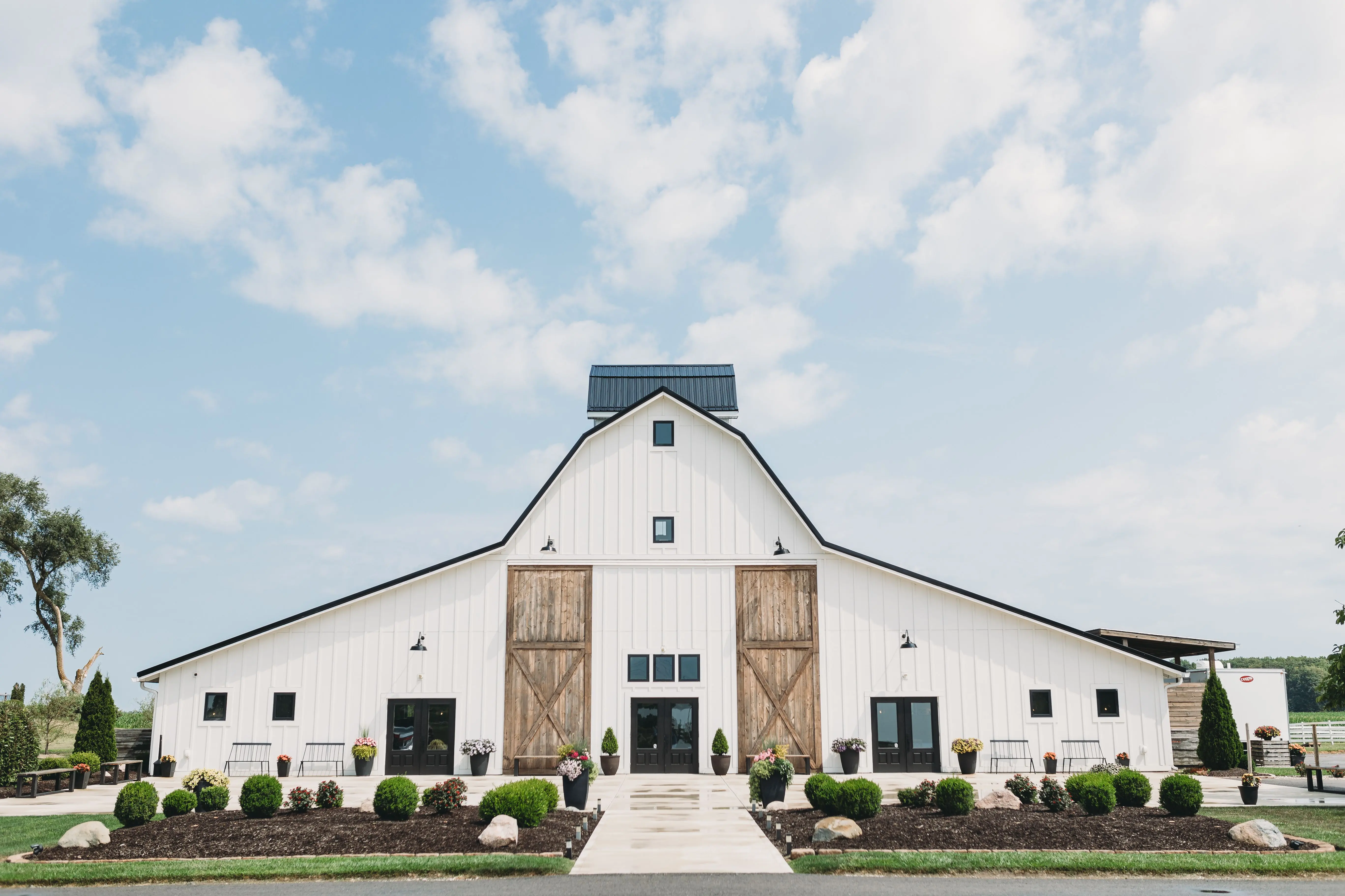 farmhouse kitchen cabinets Charming white barn under a clear blue sky, perfect for rustic weddings or countryside themed events.