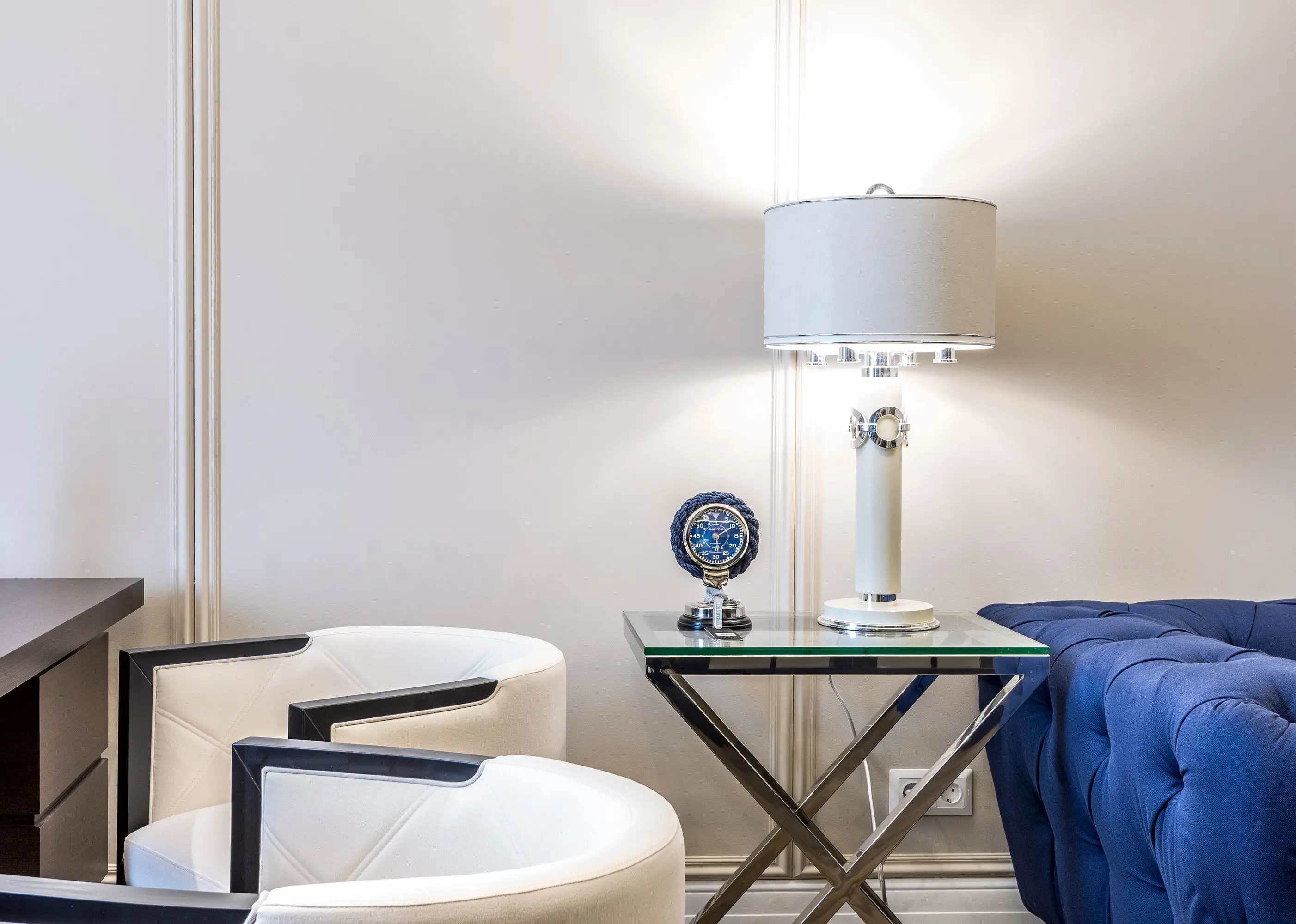white table lamp Interior of contemporary living room with small table and lamp near sofa and armchairs