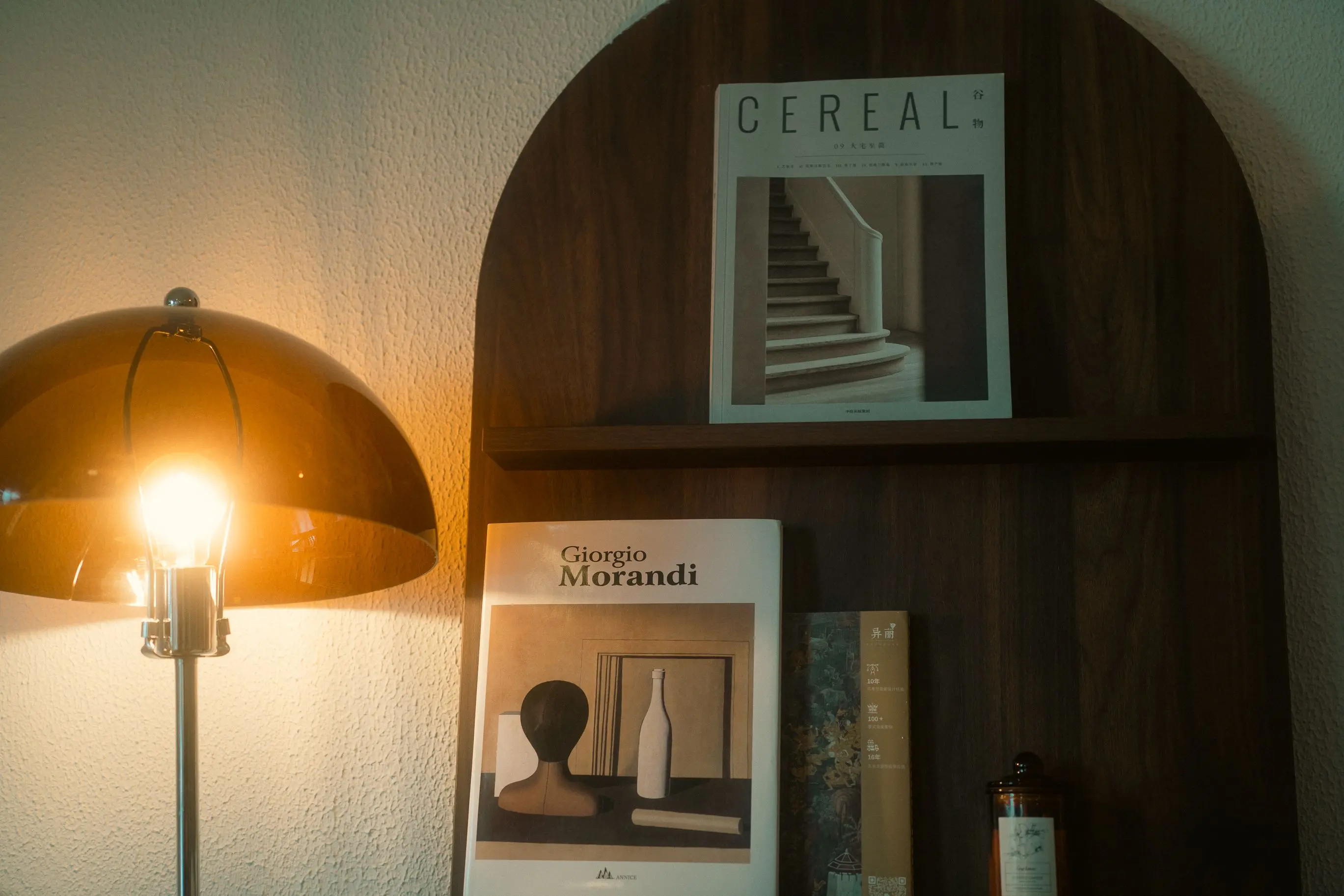 white table lamp An elegant setup featuring a modern lamp and art books on a wooden shelf, perfect for interior design inspiration.
