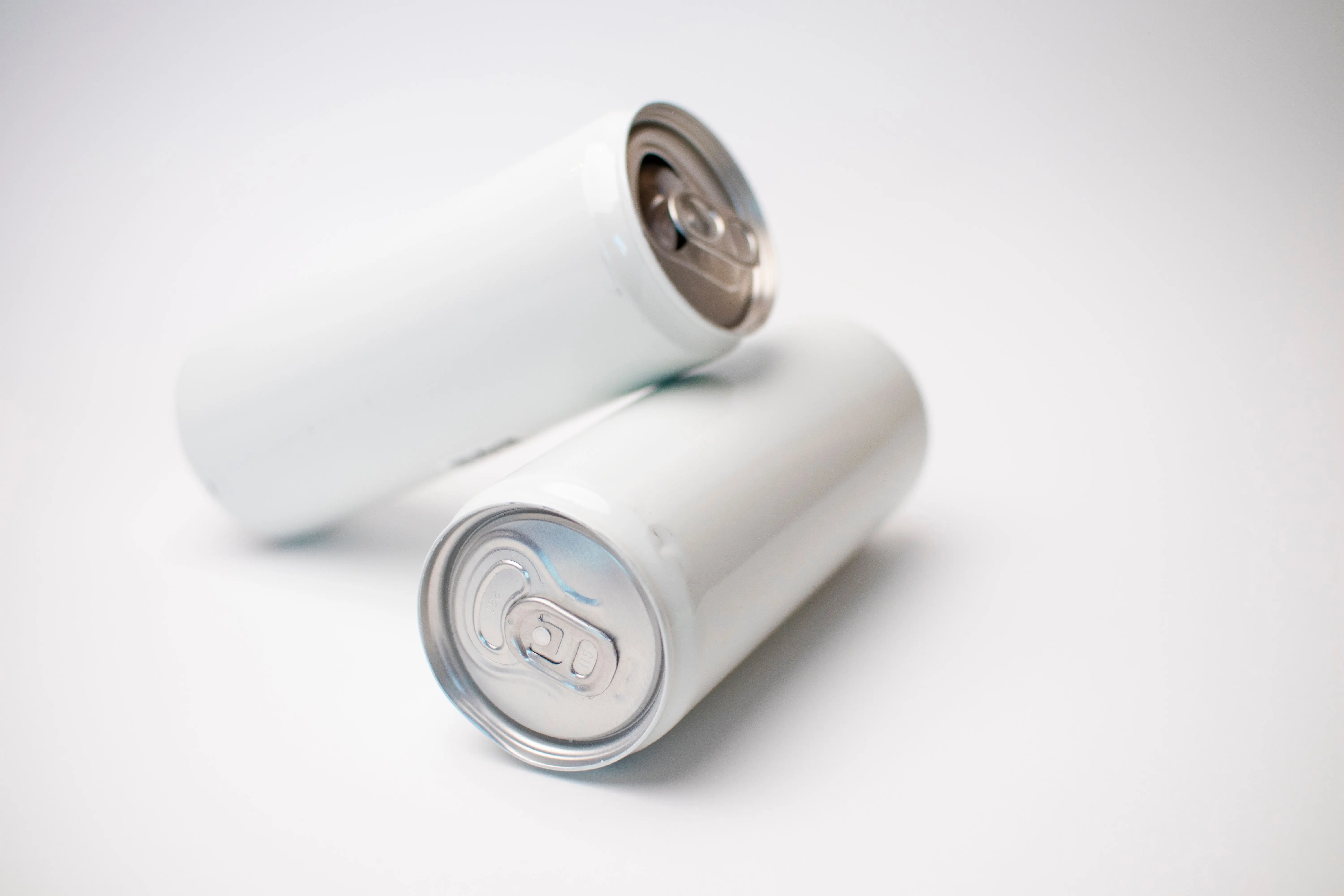 white stain Close-up of two blank aluminum cans on a white background, perfect for branding mockups.