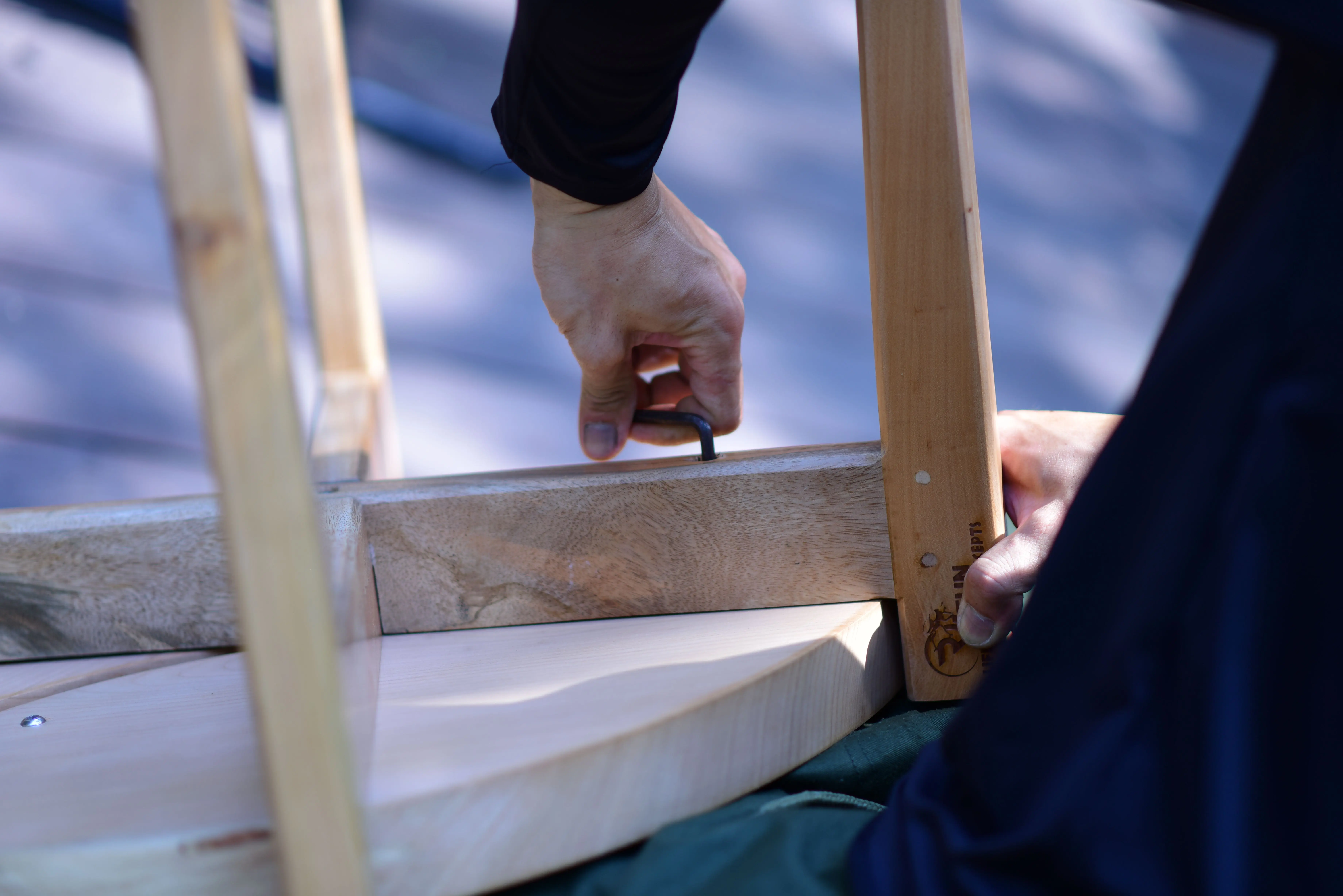 frame wood Close-up of a person assembling wooden furniture with an Allen wrench on a sunny day.