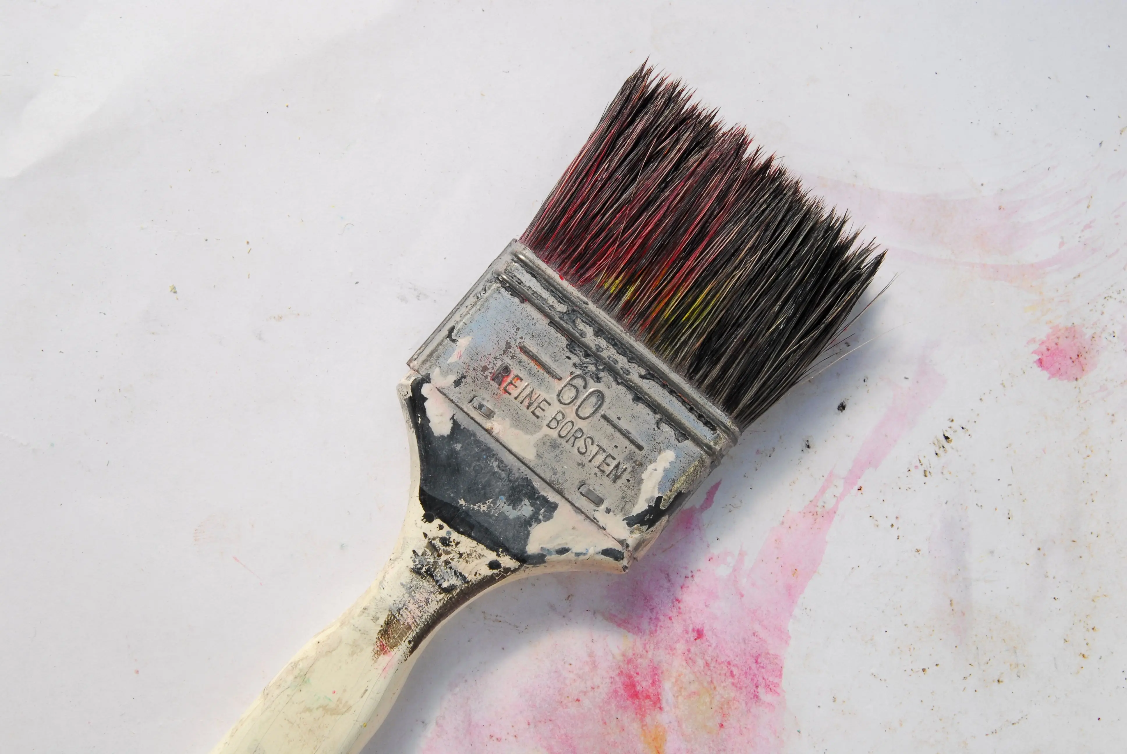 frame wood A detailed close-up of a weathered paintbrush with colorful bristles against a white background.