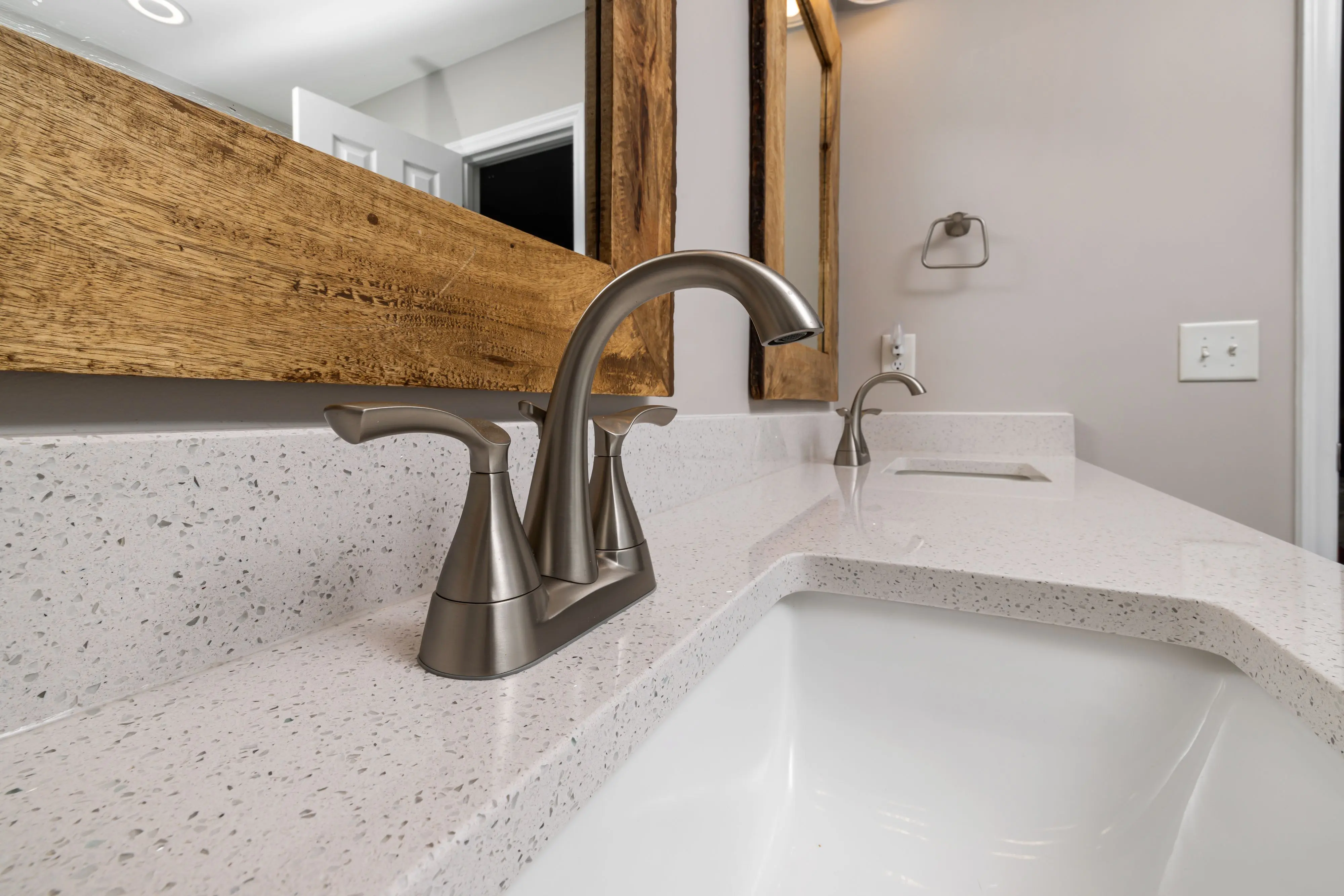 wood bathroom vanities Close-up of a contemporary bathroom sink with a sleek faucet and wooden mirror frame
