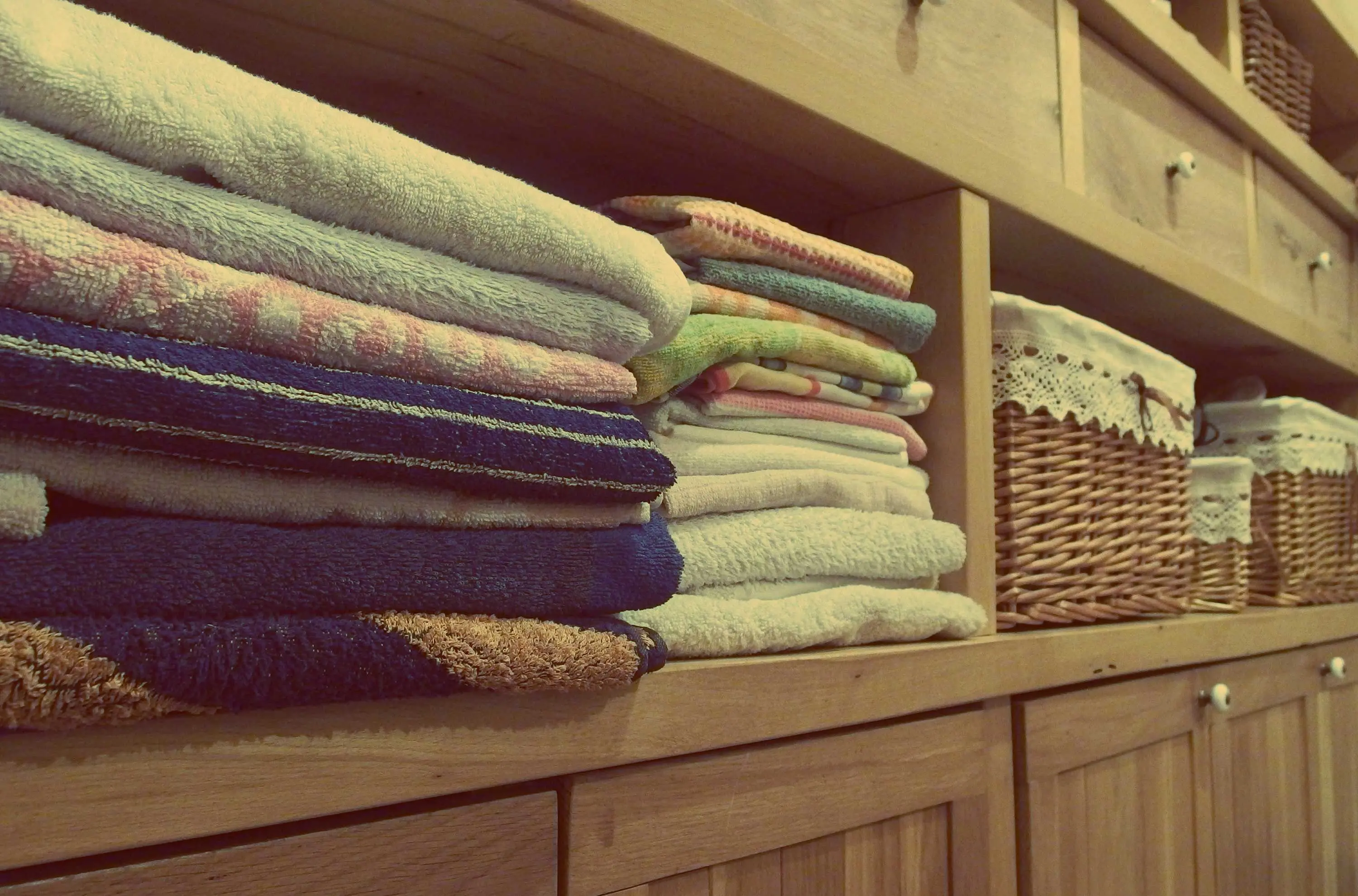 mdf cabinets Tidy wooden cabinet with neatly stacked towels and decorative baskets in an indoor setting.