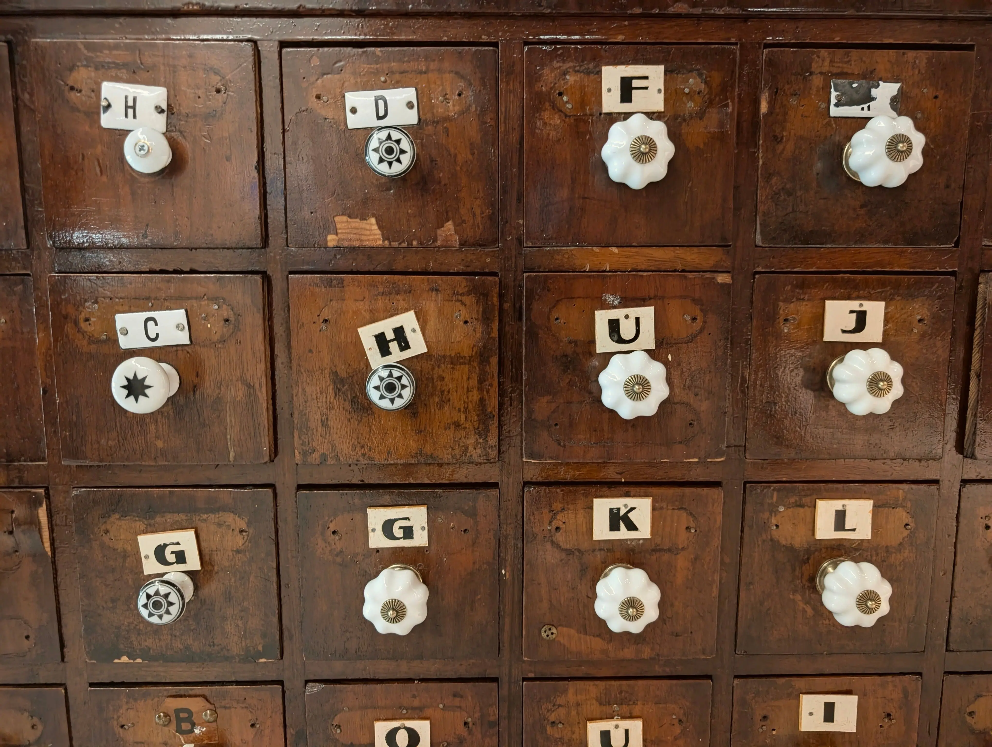 wooden drawer Antique wooden drawer cabinet with unique labeled knobs in a vintage style.