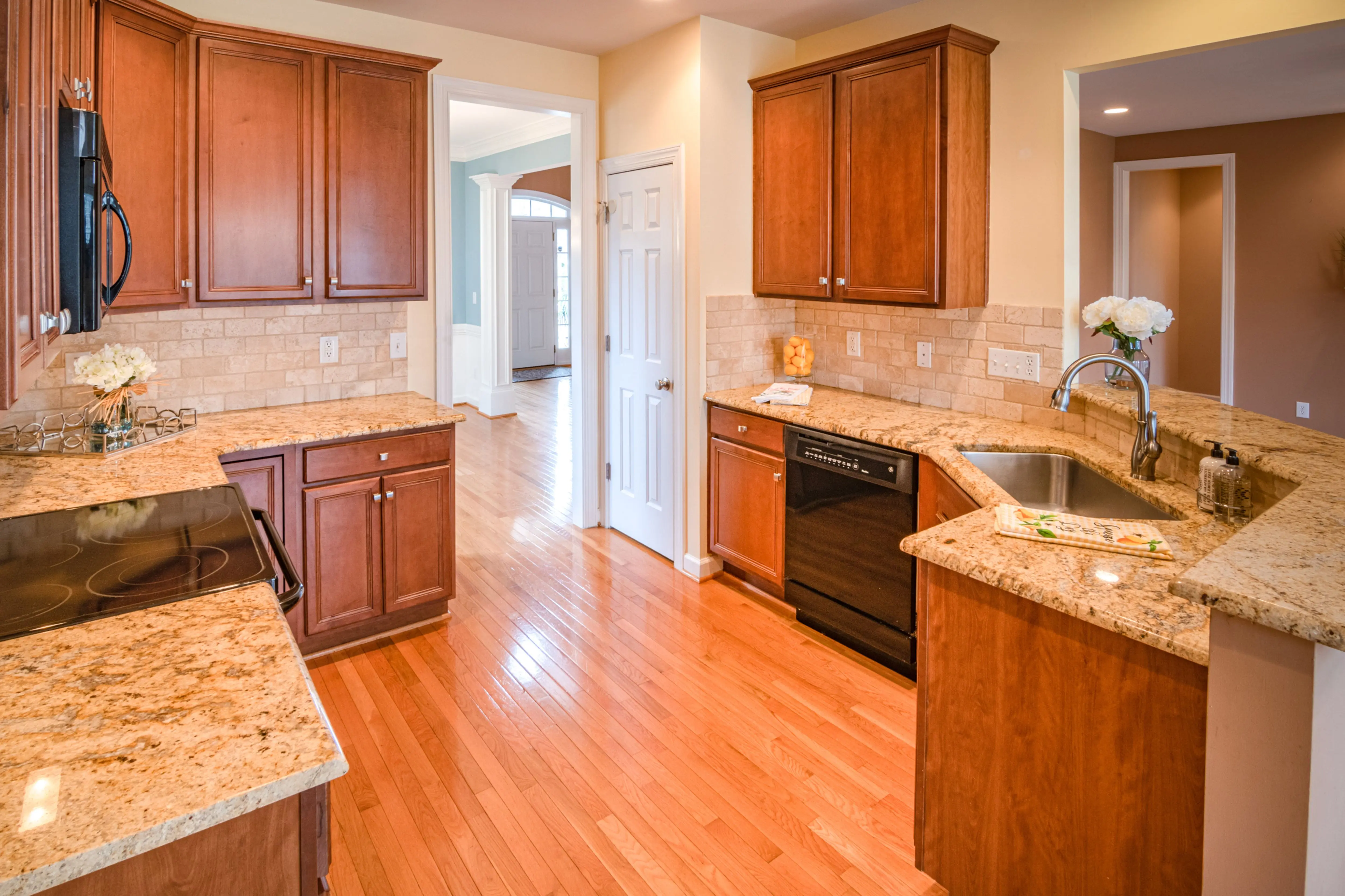 cherry wood cabinets Bright kitchen interior with wooden cabinets and granite countertops.