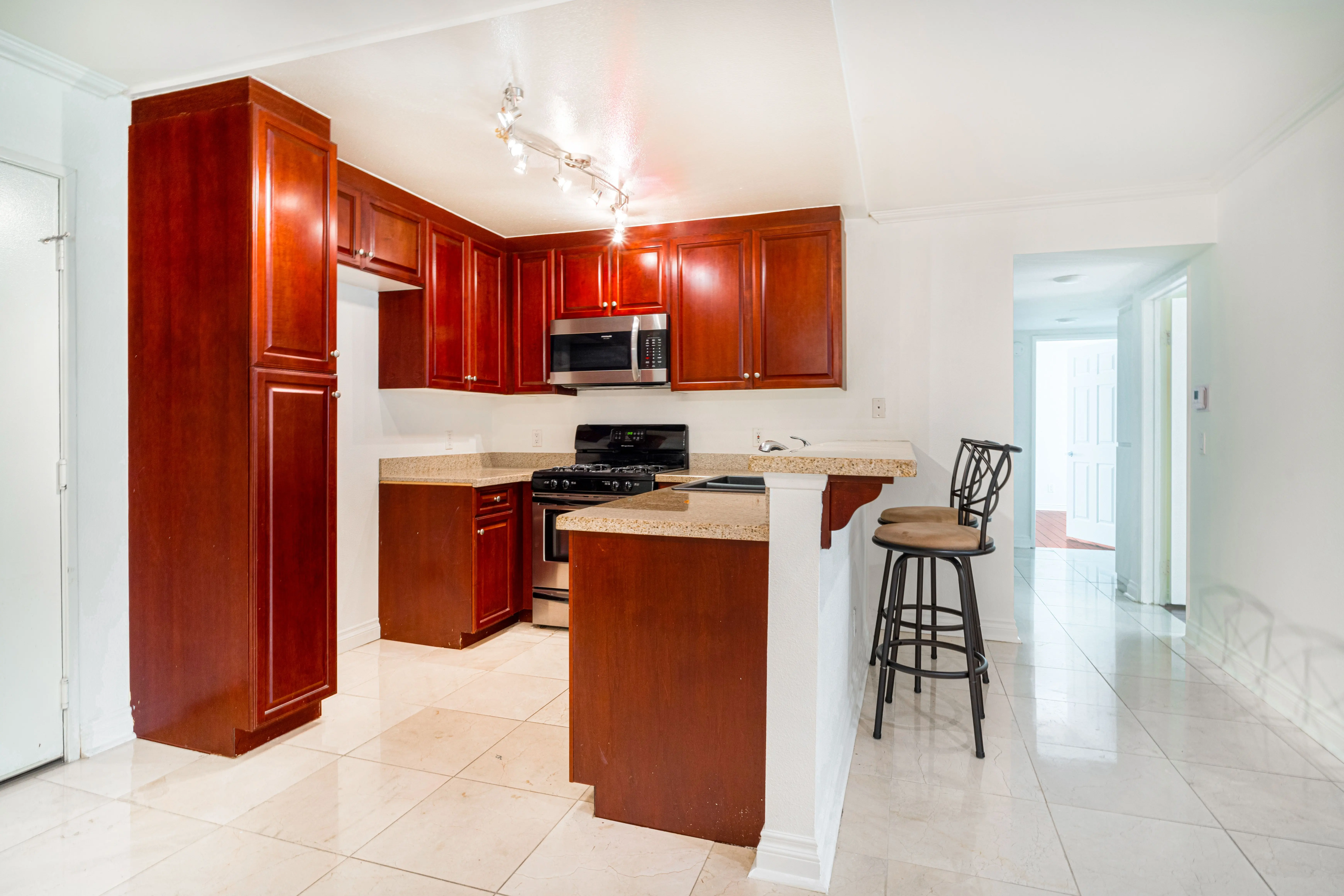 cherry wood cabinets Sleek kitchen interior with cherry wood cabinets, granite countertops, and stainless steel appliances.