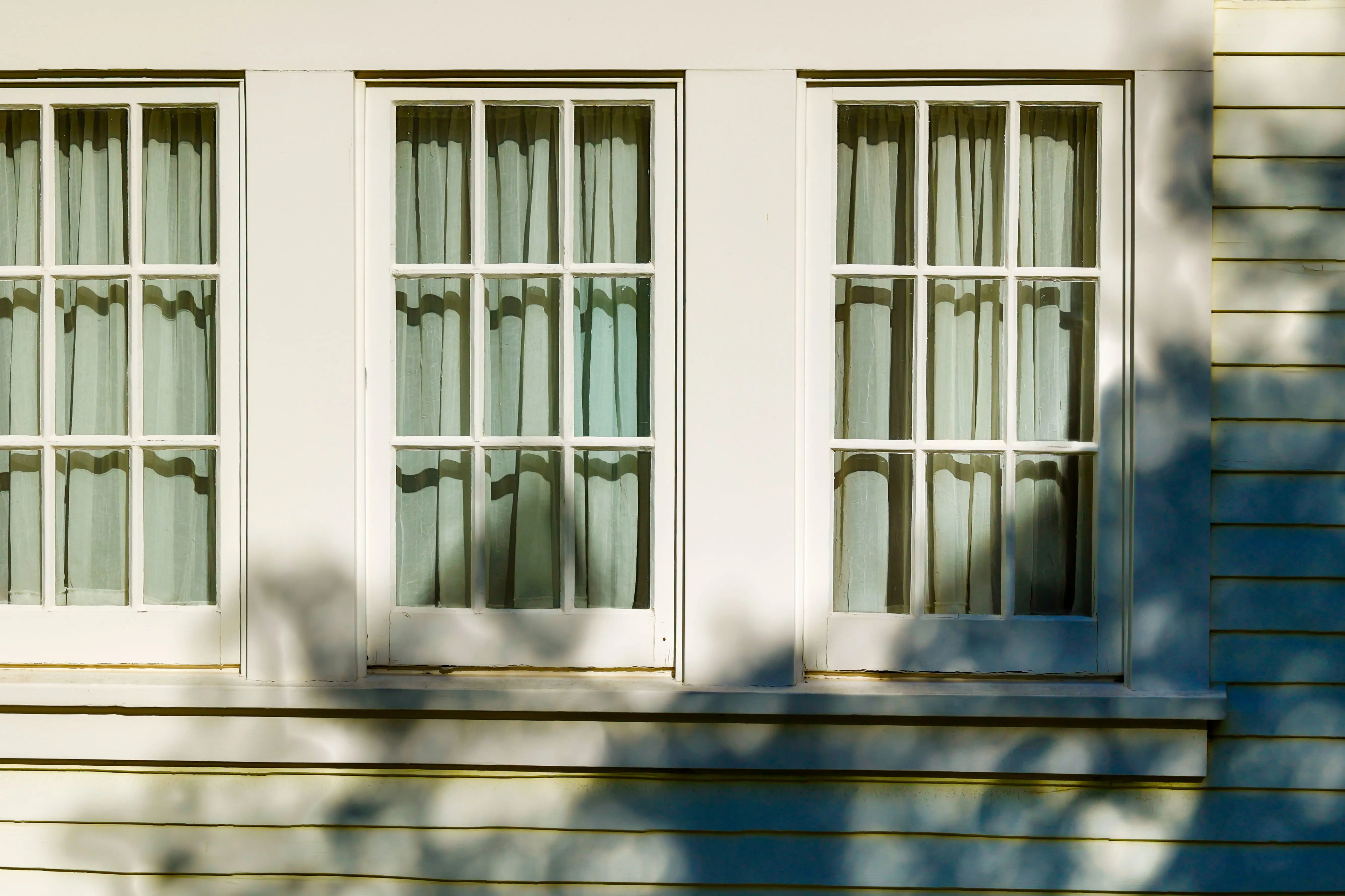 white vinyl siding Stylish facade featuring classic French windows with soft shadows and light play.