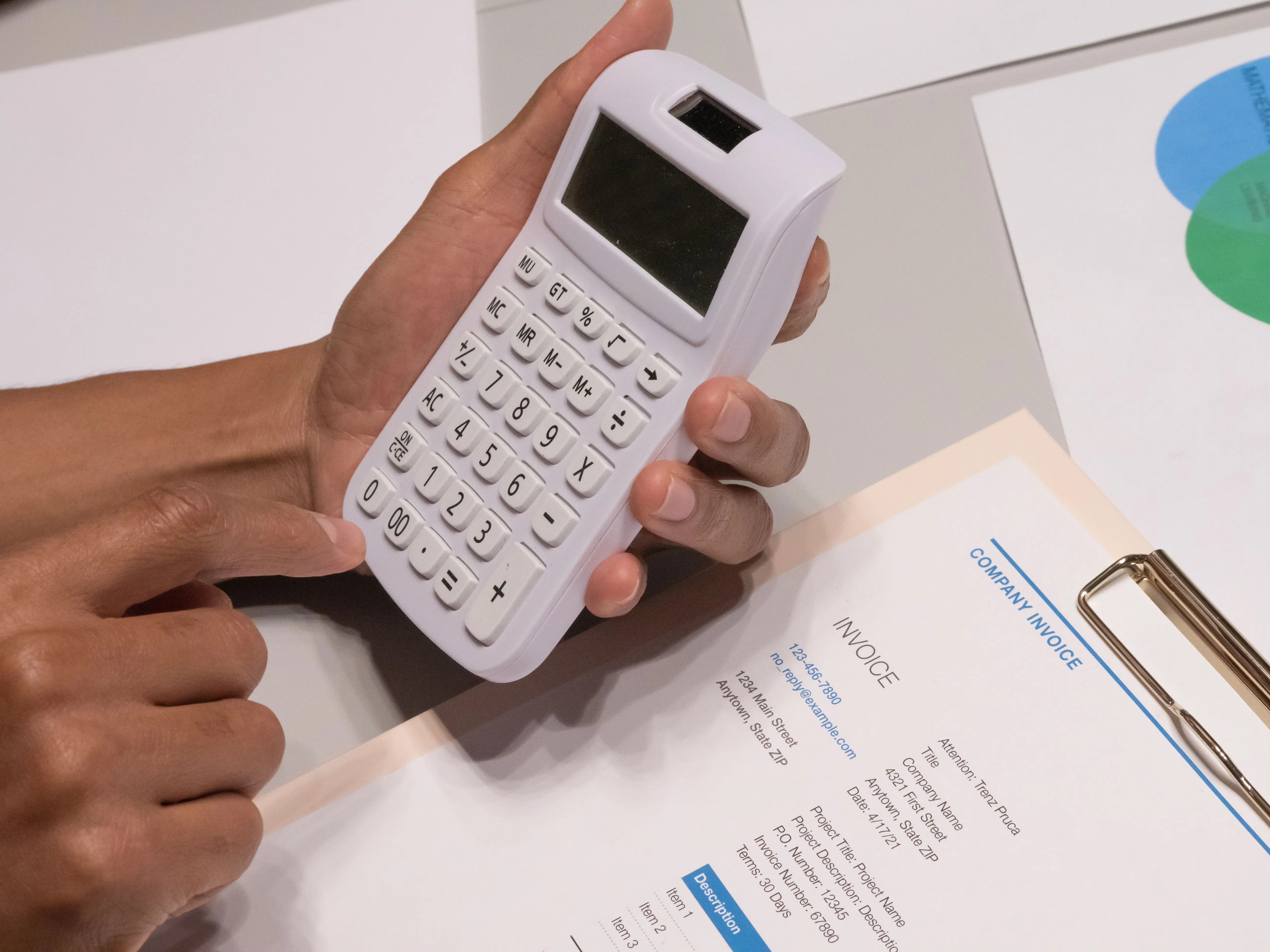 house addition cost Close-up of hands using a calculator next to a company invoice, depicting a financial calculation concept.