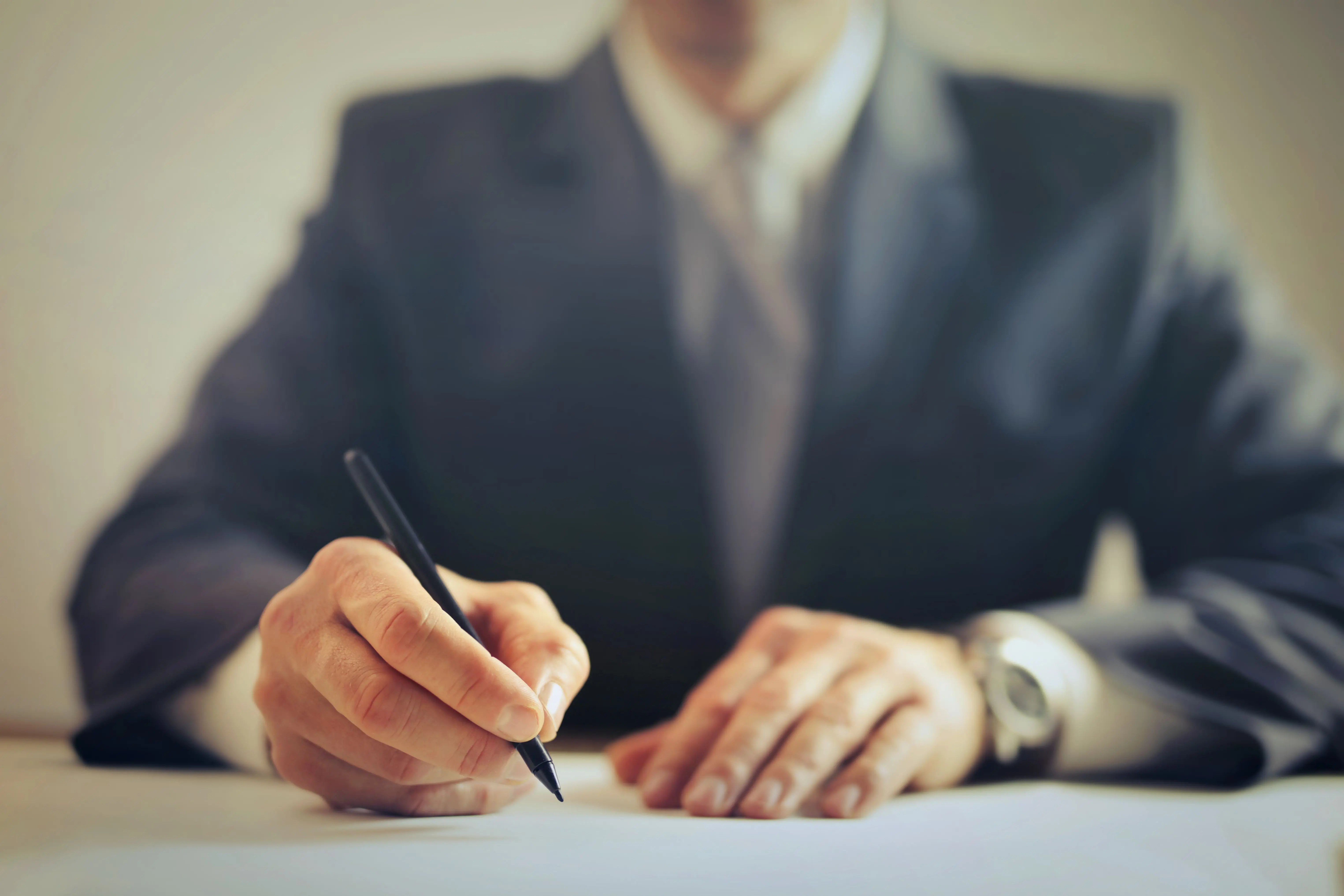 basement remodel cost Male entrepreneur wearing formal suit sitting at table in workplace and signing documents while making successful business deal