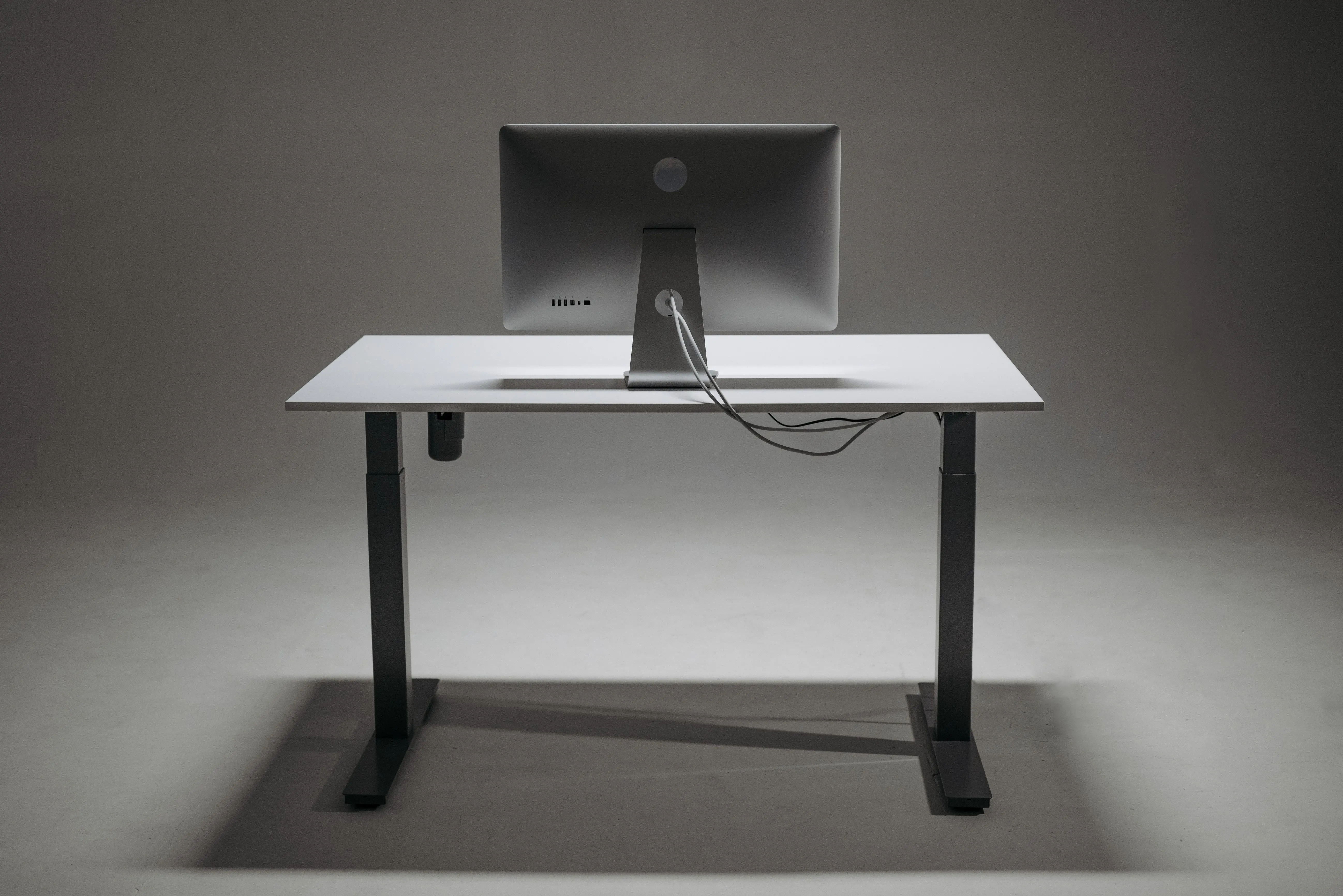 metal desk legs Rear view of a modern height adjustable standing desk with monitor and cable management.