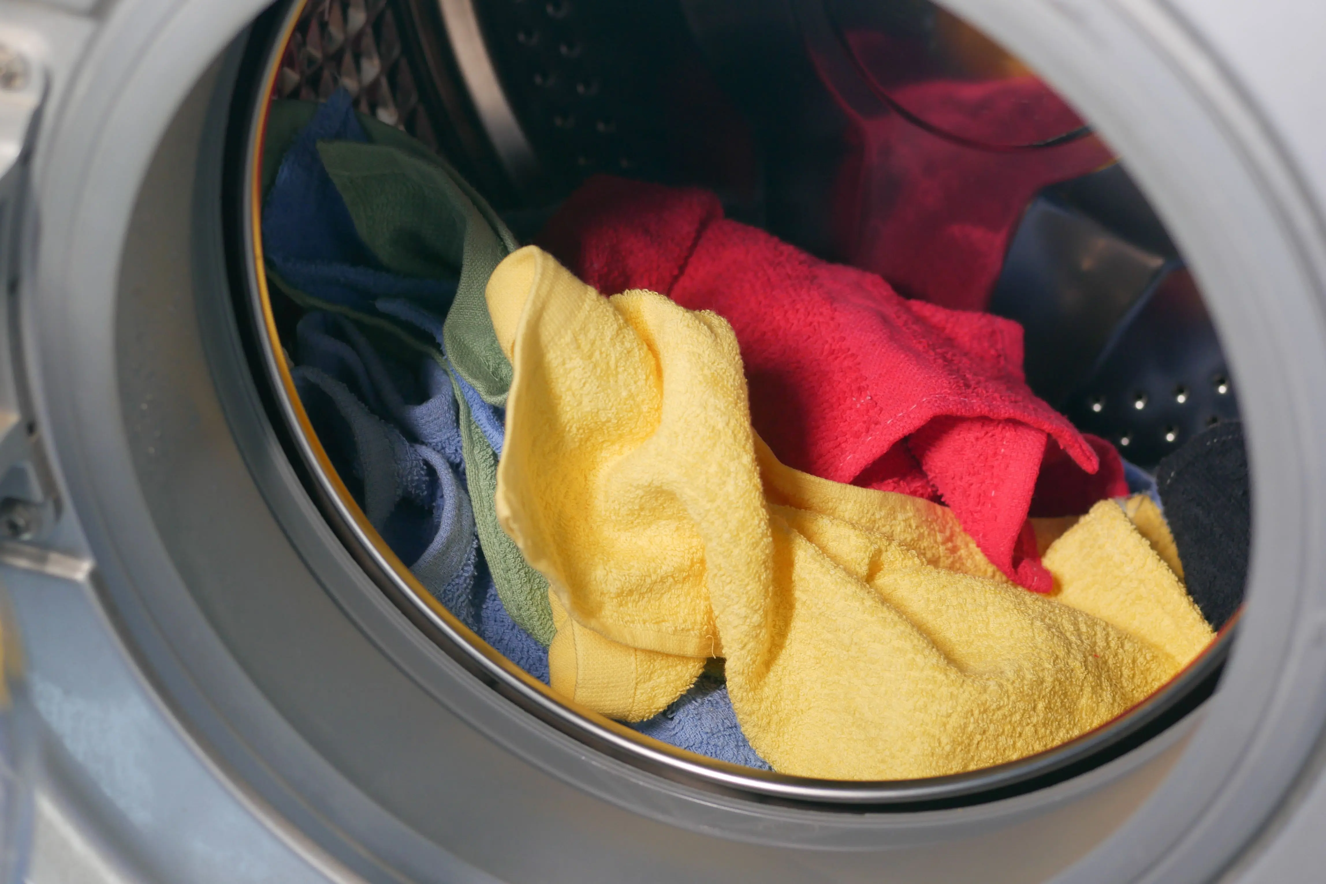 how to get dried blood out of clothes Vibrant close-up of multicolored towels inside a washing machine, ready for a wash.