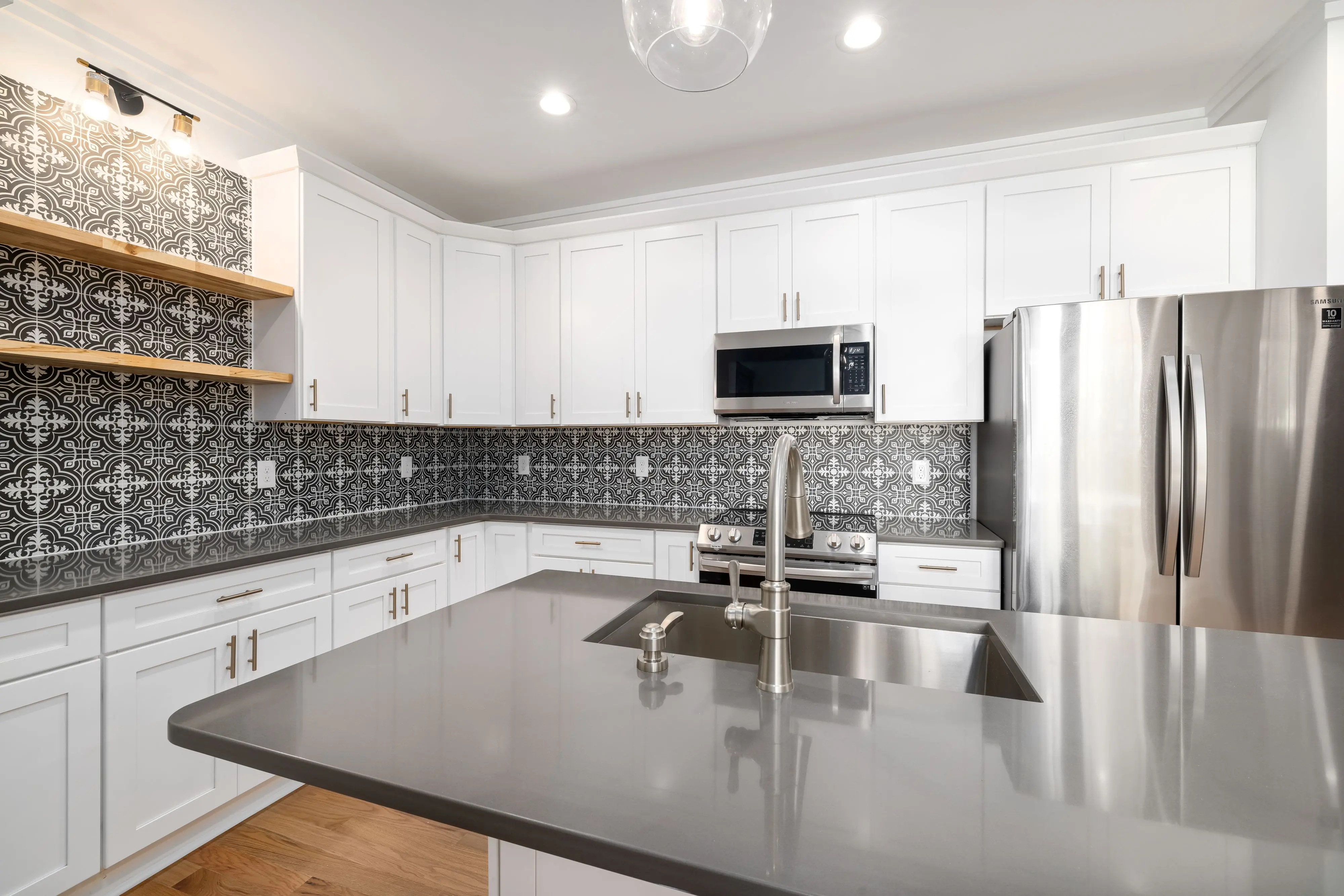 green tile backsplash Stylish white kitchen featuring a geometric tile backsplash and stainless steel appliances.