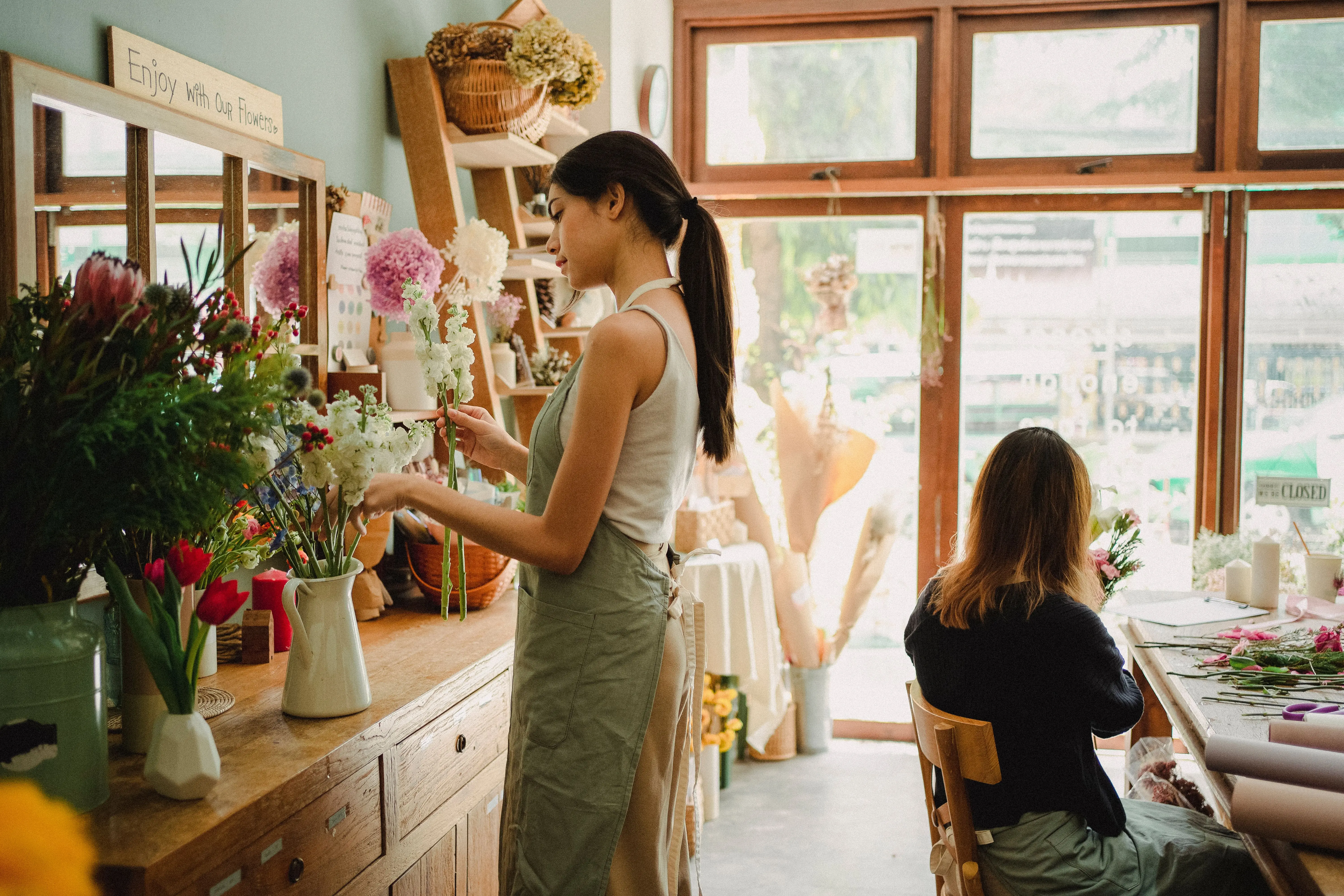 flowers in vase Concentrated women in casual clothes and aprons making bouquets of fresh flowers while working in cozy floristry studio