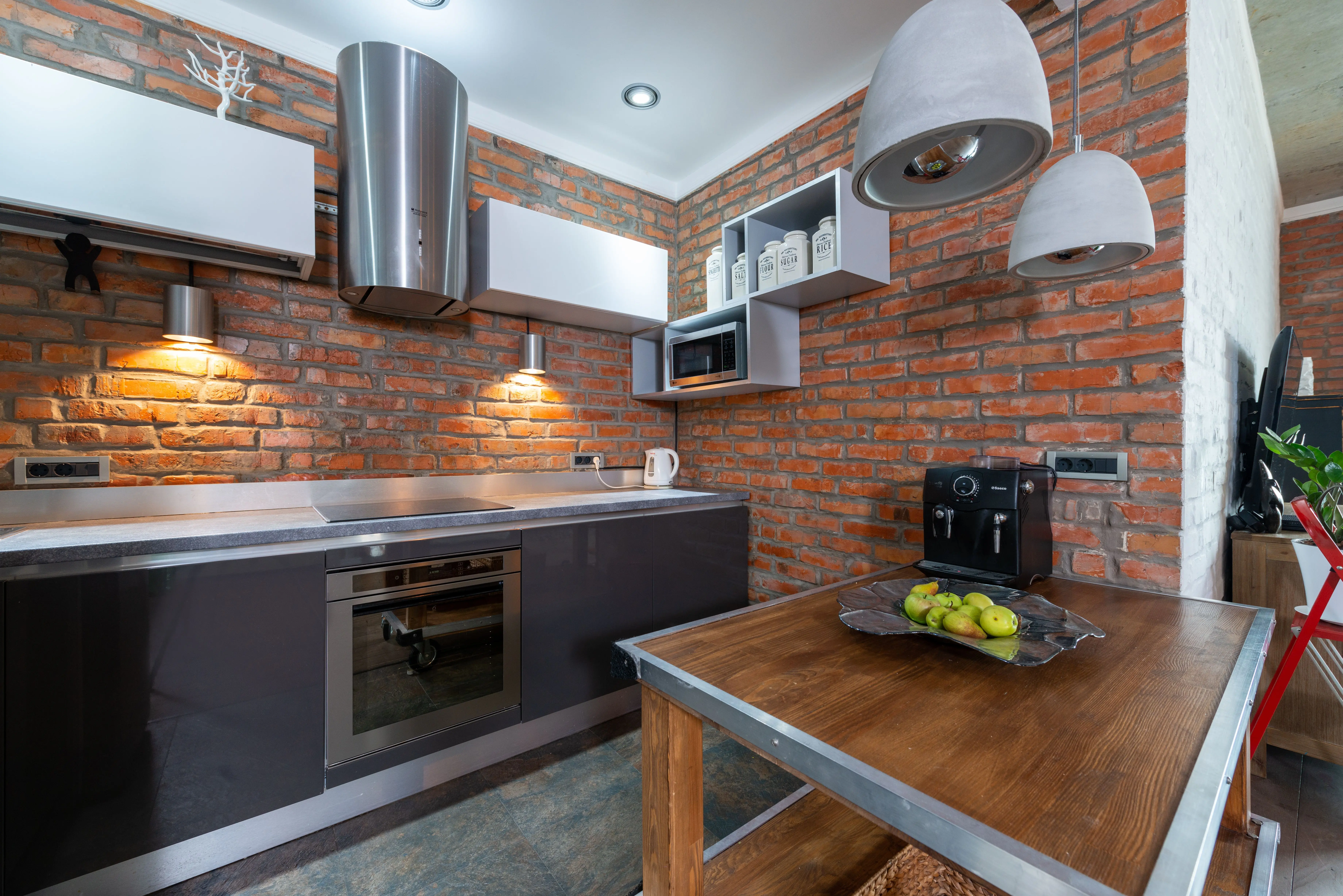 industrial furniture Contemporary kitchen interior featuring red brick walls and modern appliances.
