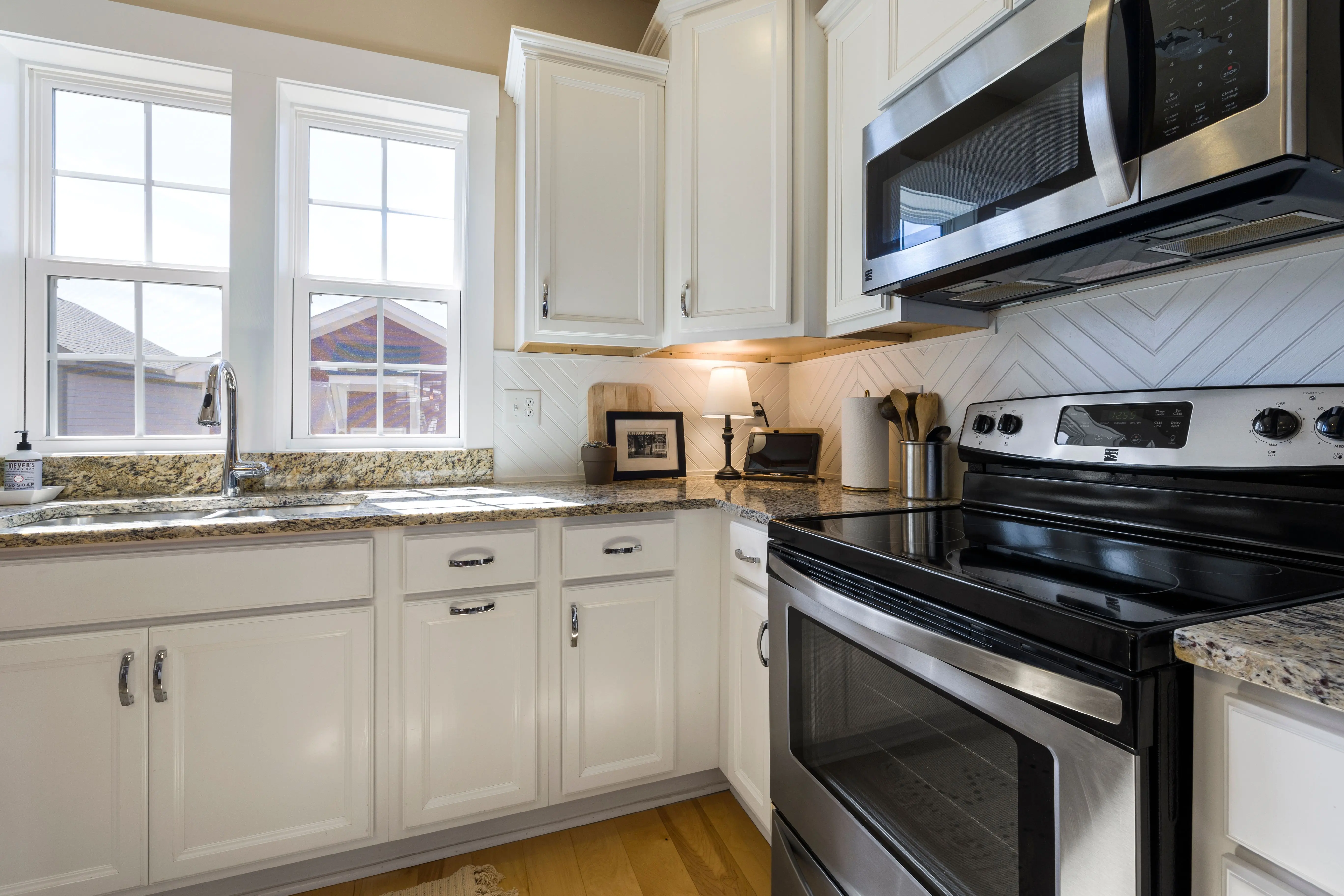 cherry wood kitchen cabinets Bright and stylish modern kitchen featuring white cabinets and granite countertops with stainless steel appliances.