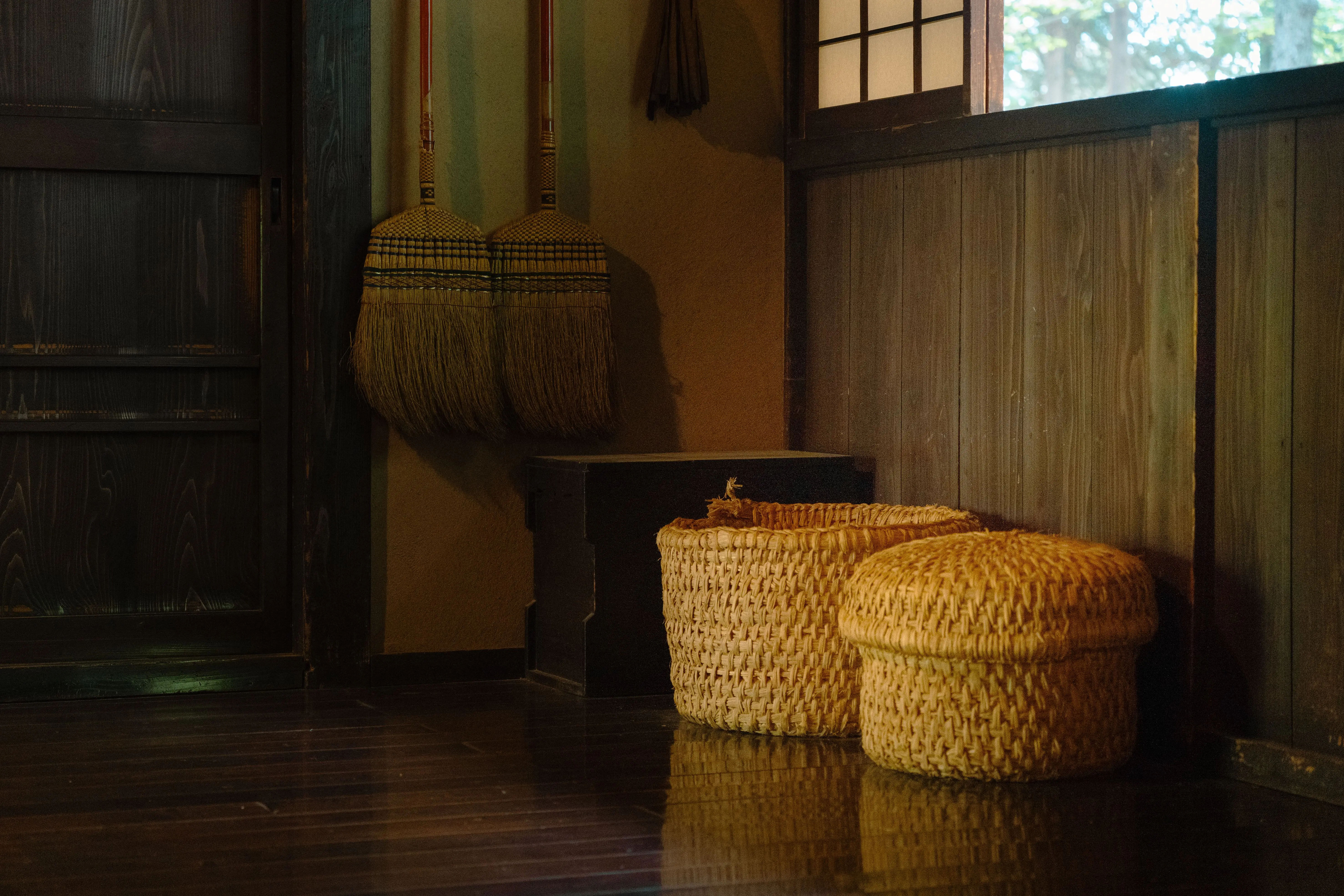 large baskets Cozy Japanese room featuring woven baskets and traditional brooms in dim lighting.