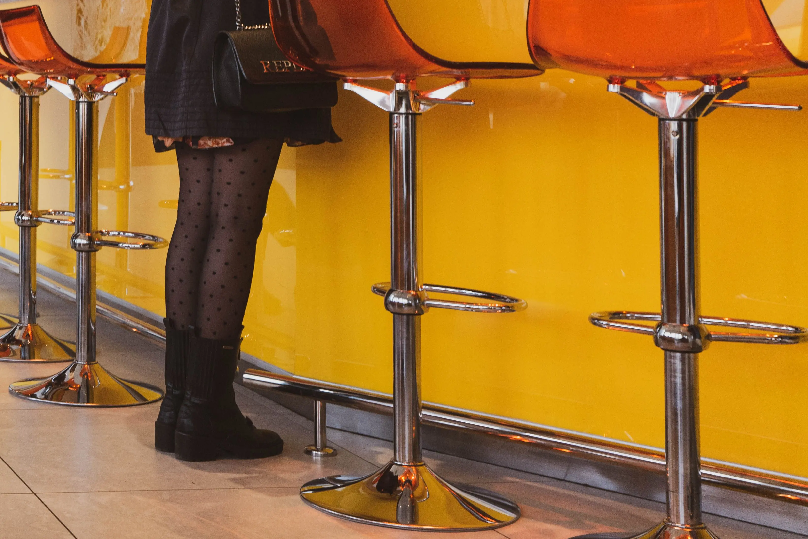 metal desk legs A woman stands at a modern bar counter wearing stylish polka dot tights and black boots.