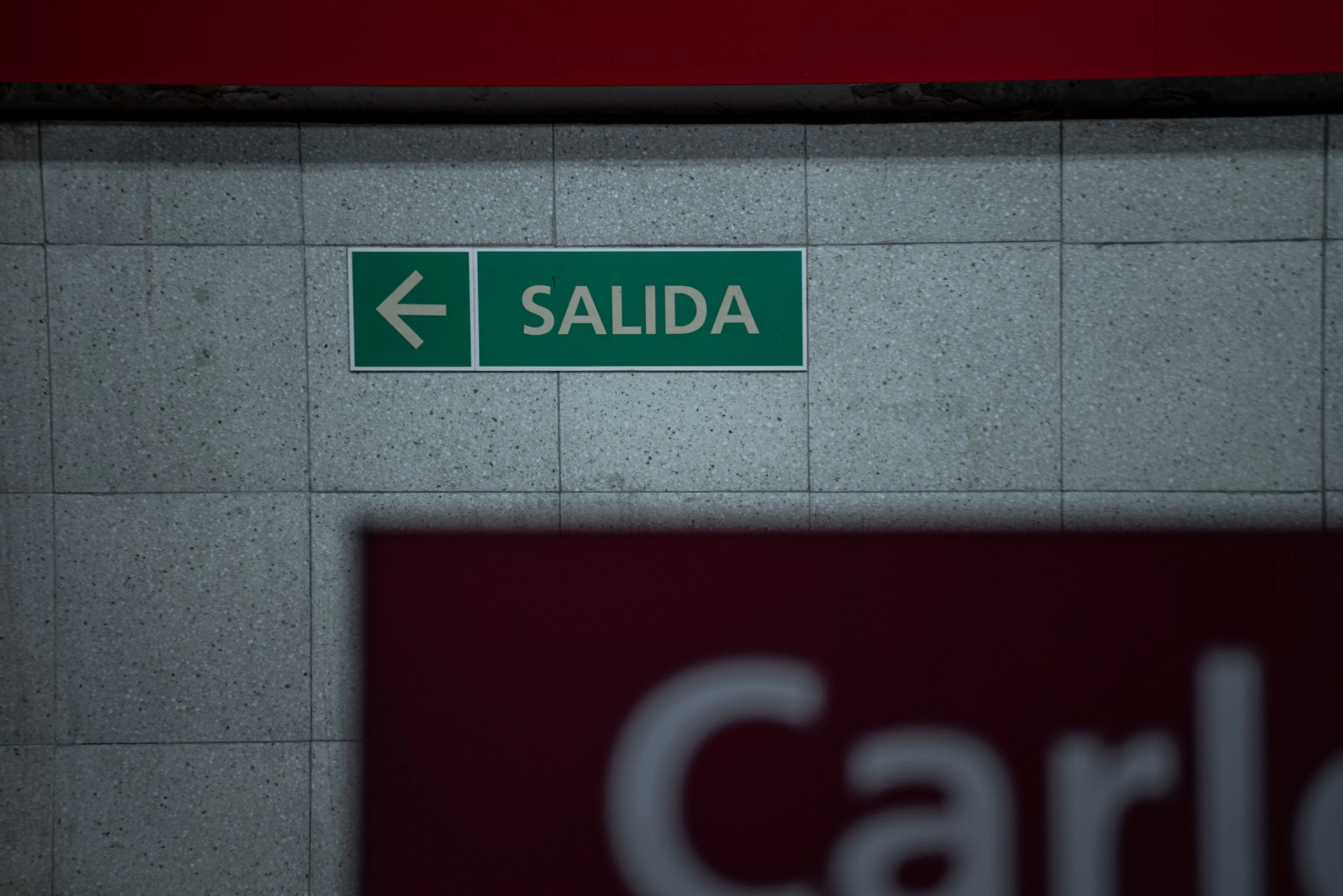 green backsplash Green exit sign in a Buenos Aires subway, indicating direction with arrow.