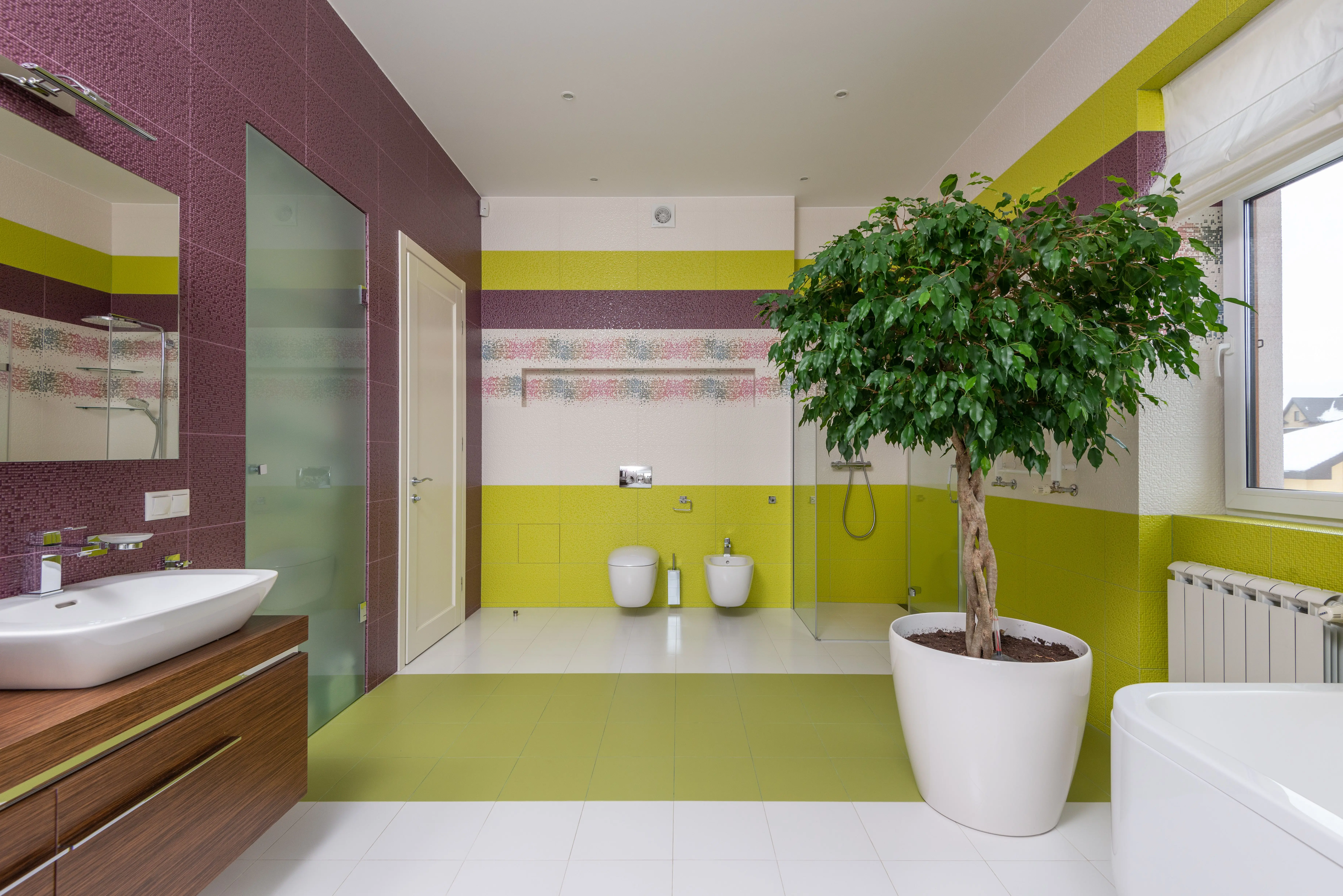 green shower tile Interior of modern master bathroom with colourful walls and ceramic sink with mirror and potted plant near window