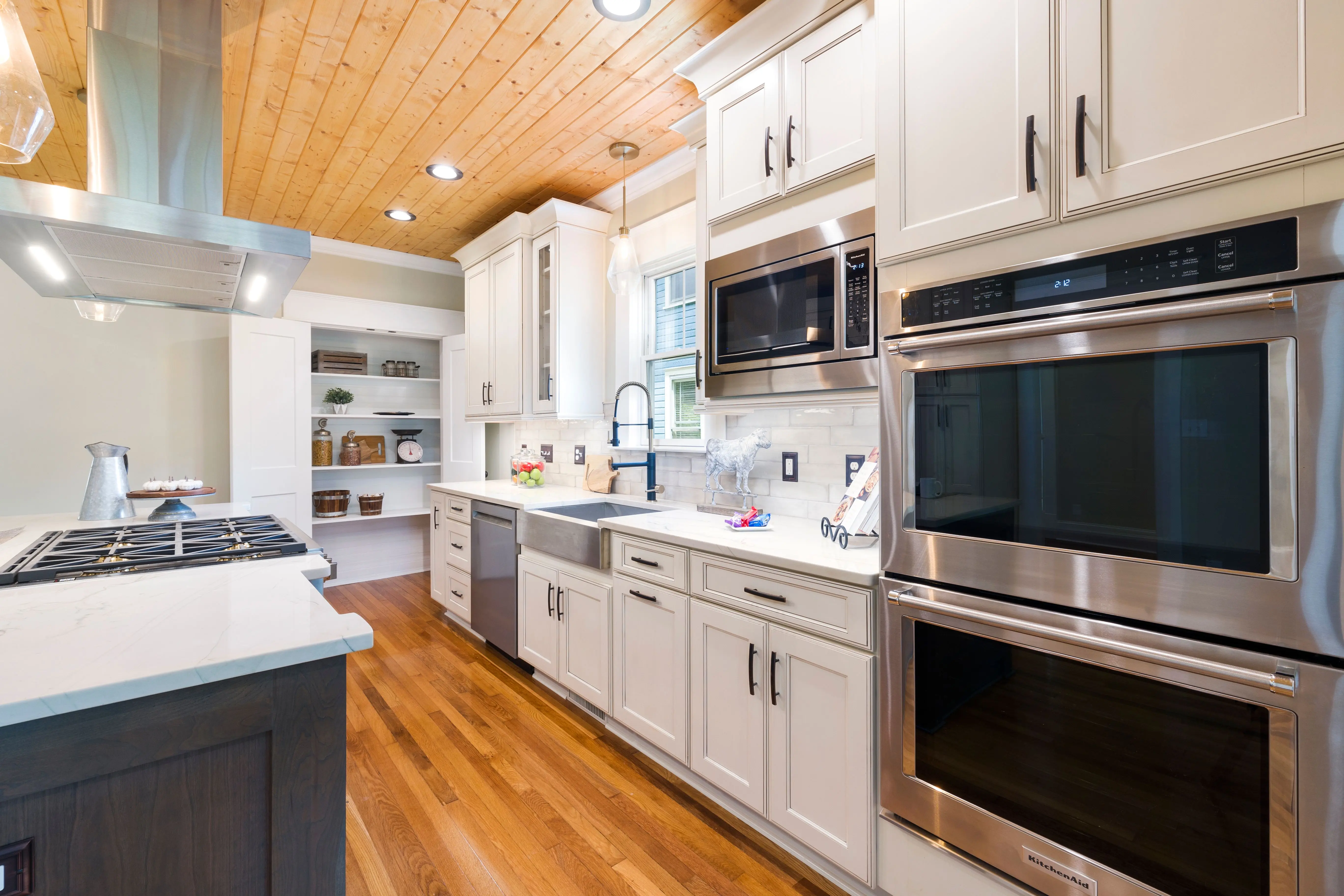 white shaker kitchen cabinets Spacious modern kitchen design featuring white cabinets, wooden floors, and stainless steel appliances.