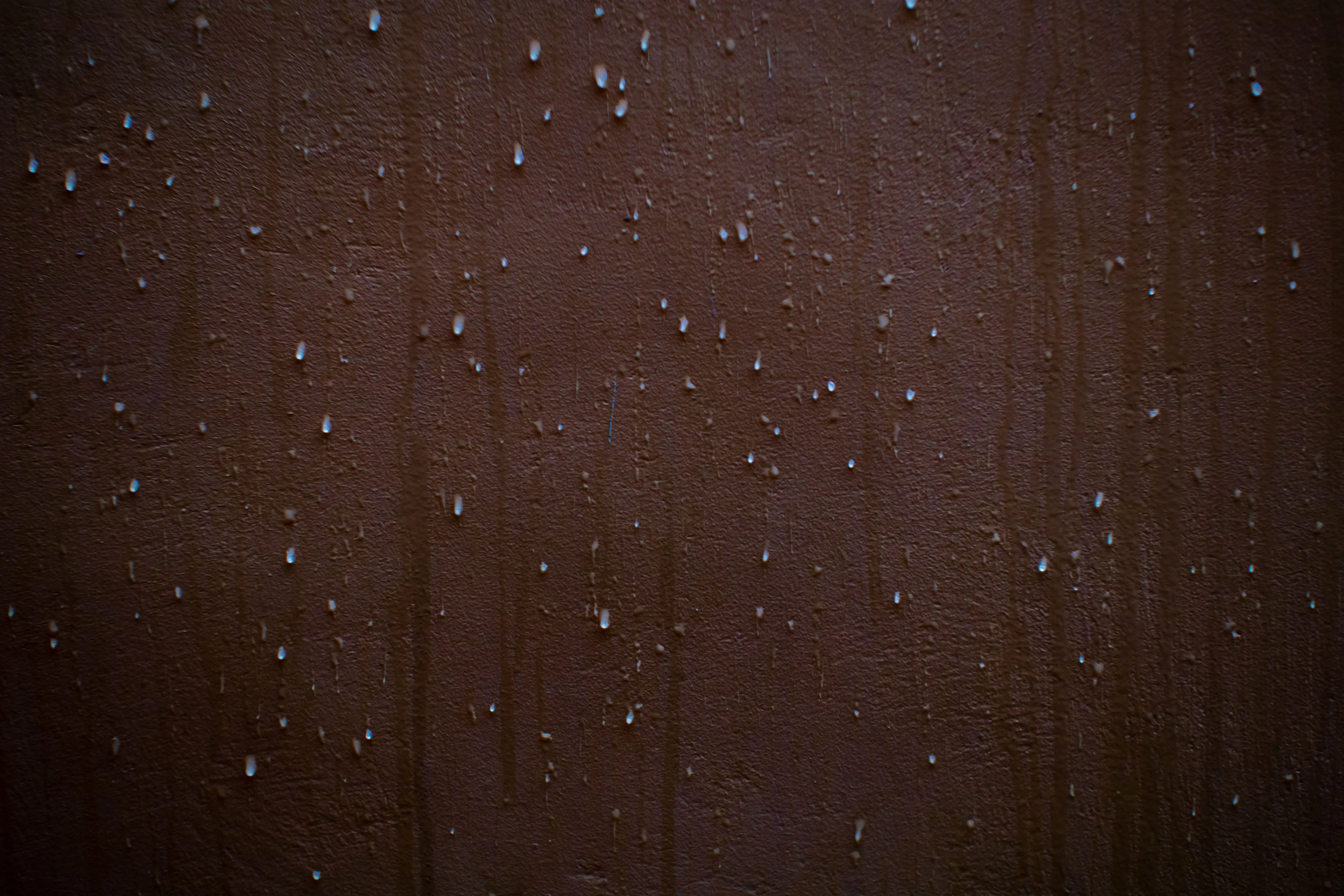 mouse in wall Detailed view of water droplets creating a texture on a brown wall surface.